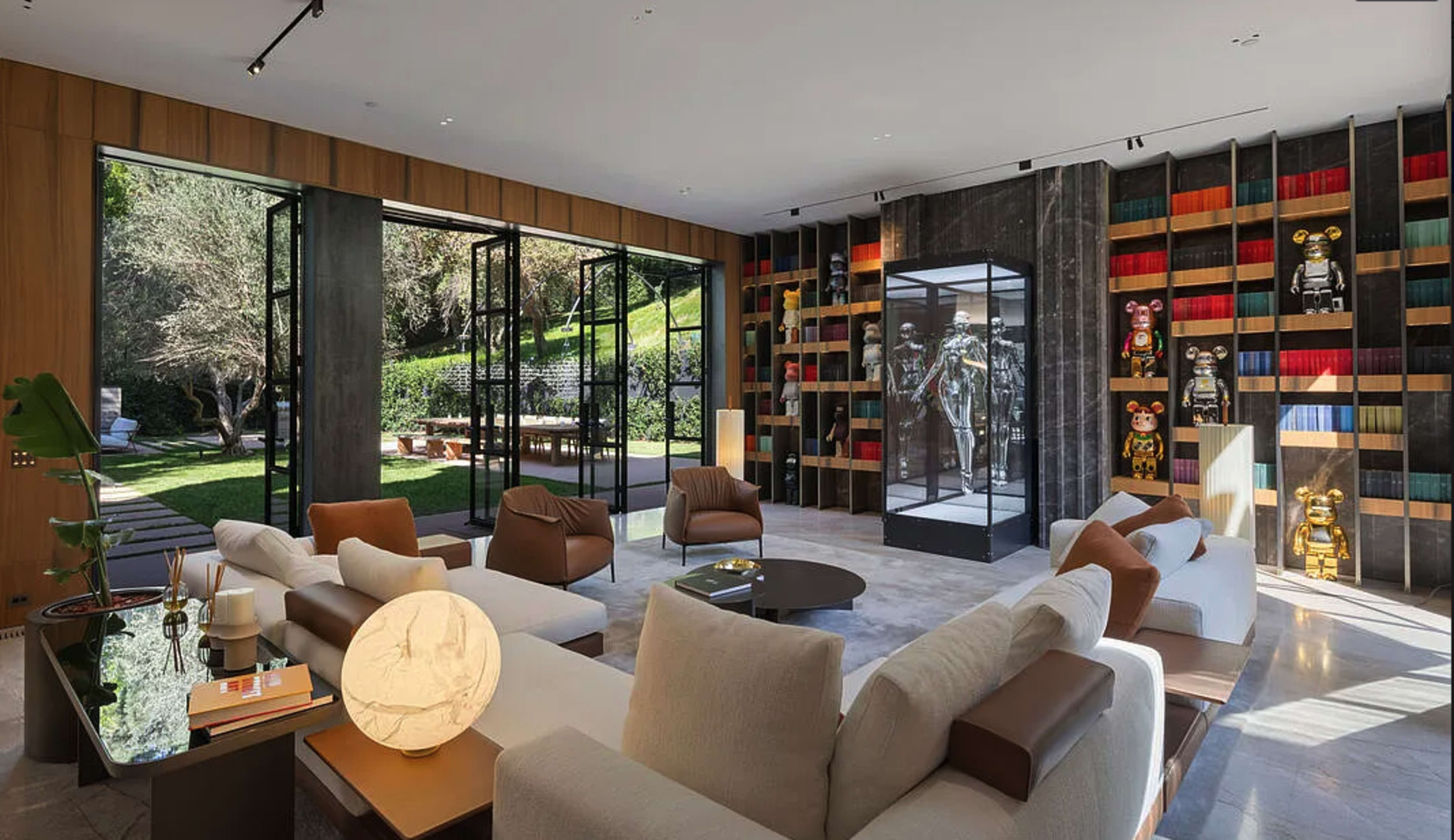 The image shows a modern living room with large glass doors leading to a garden, featuring a display of art toys and decorative shelves.