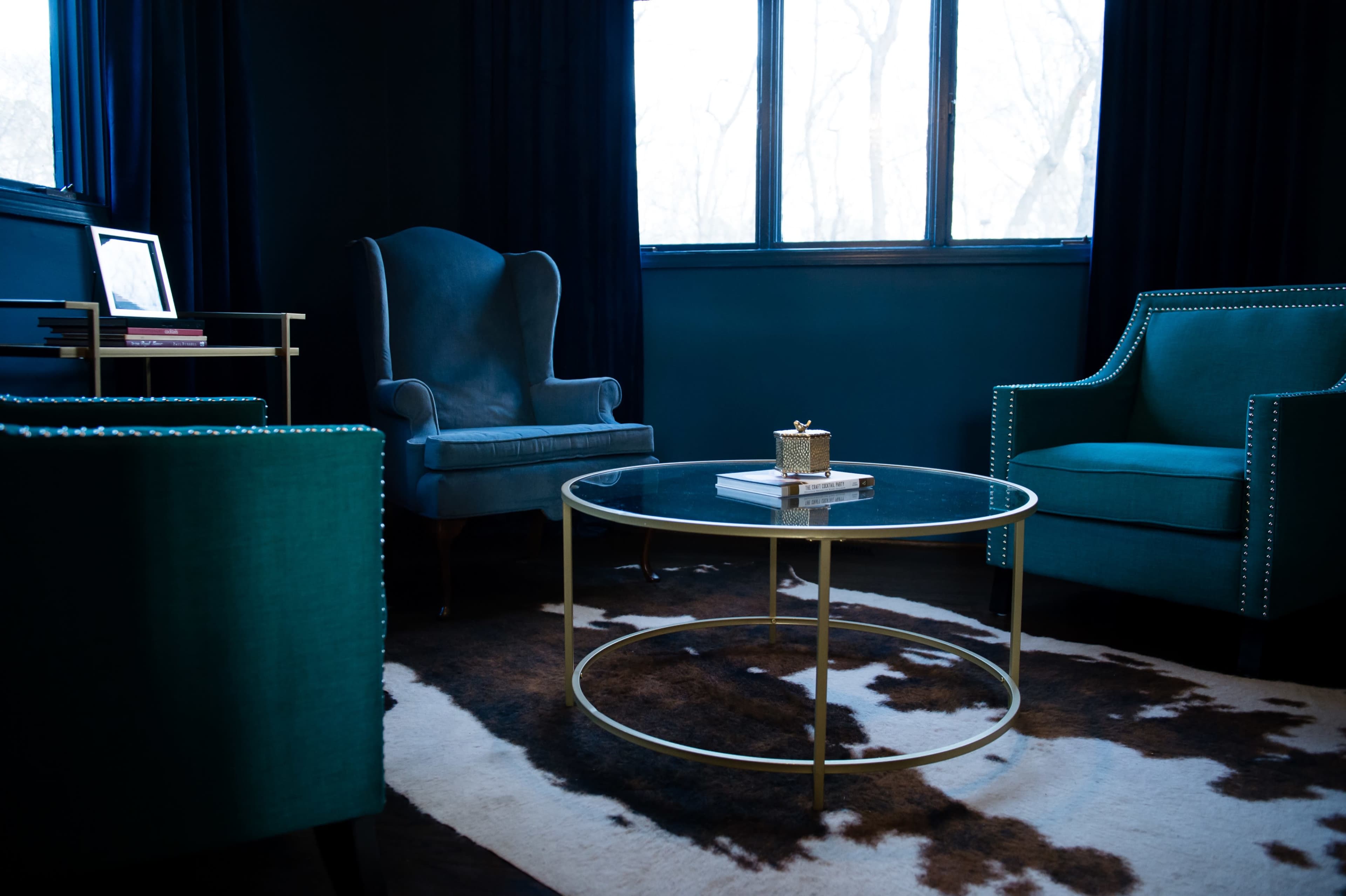 A stylish room with two upholstered chairs, a glass coffee table, and large windows letting in natural light.