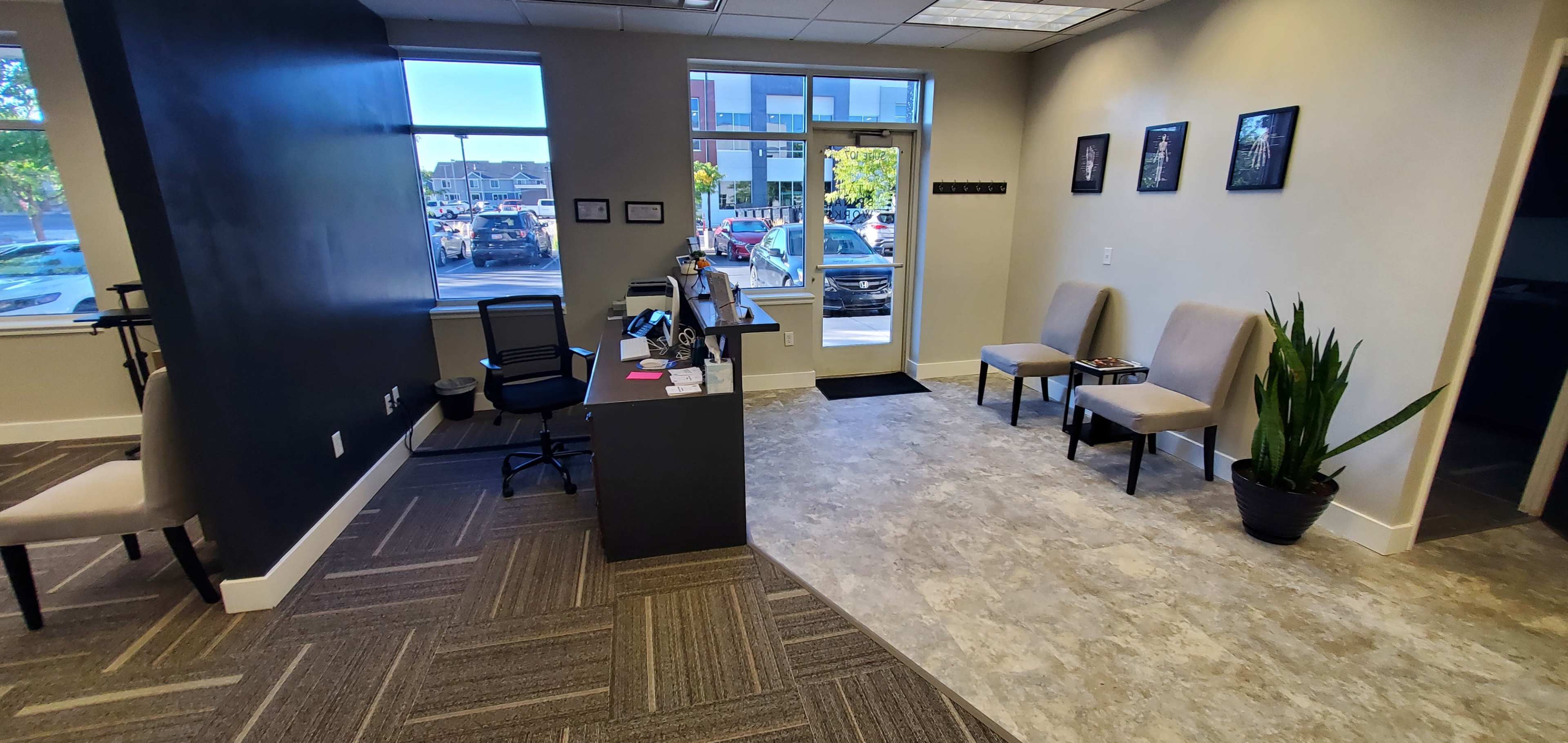 A reception area with a desk, two chairs, and a large window showing an outdoor view.