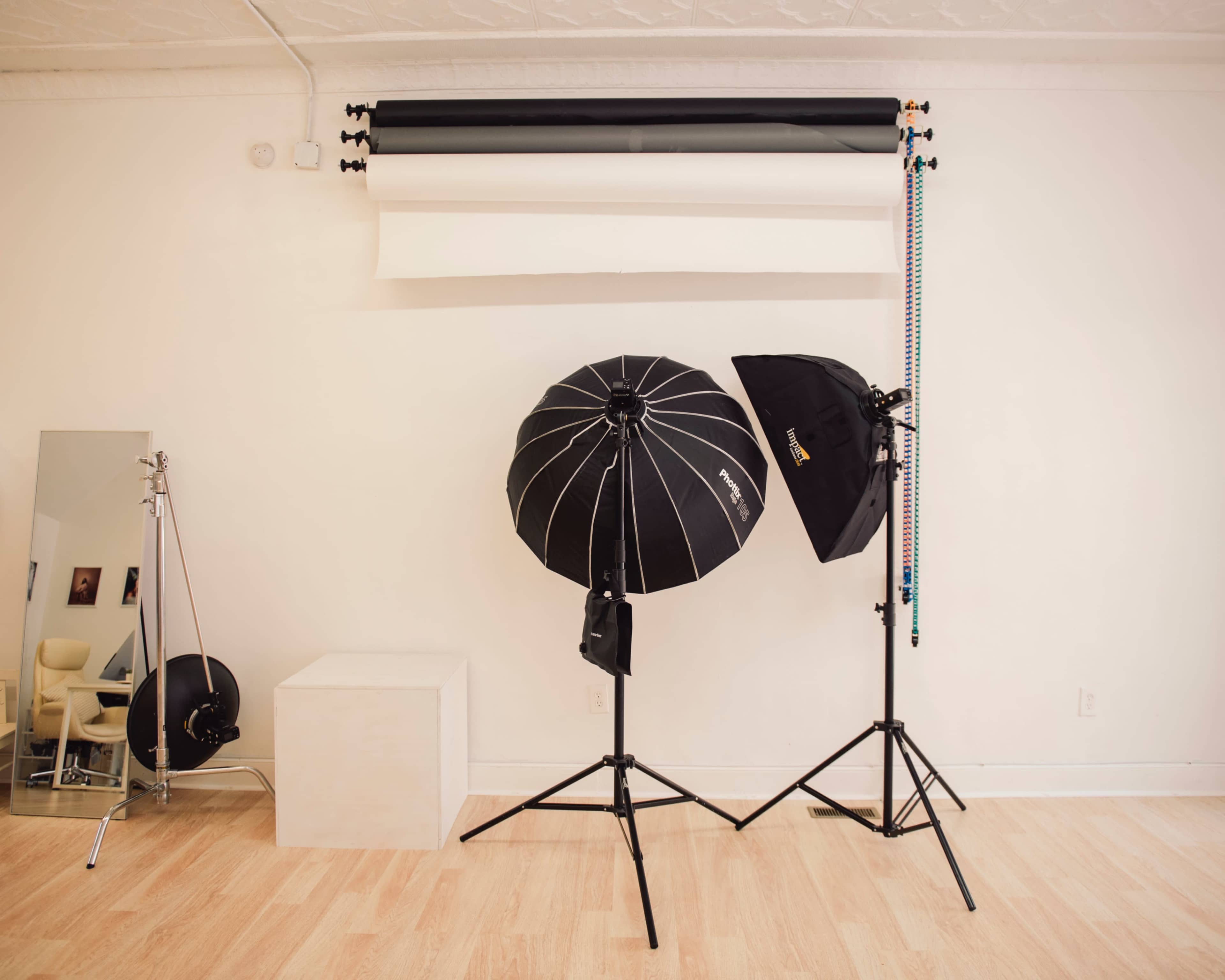 A photography studio setup with two light stands, a white background, and various lighting equipment.