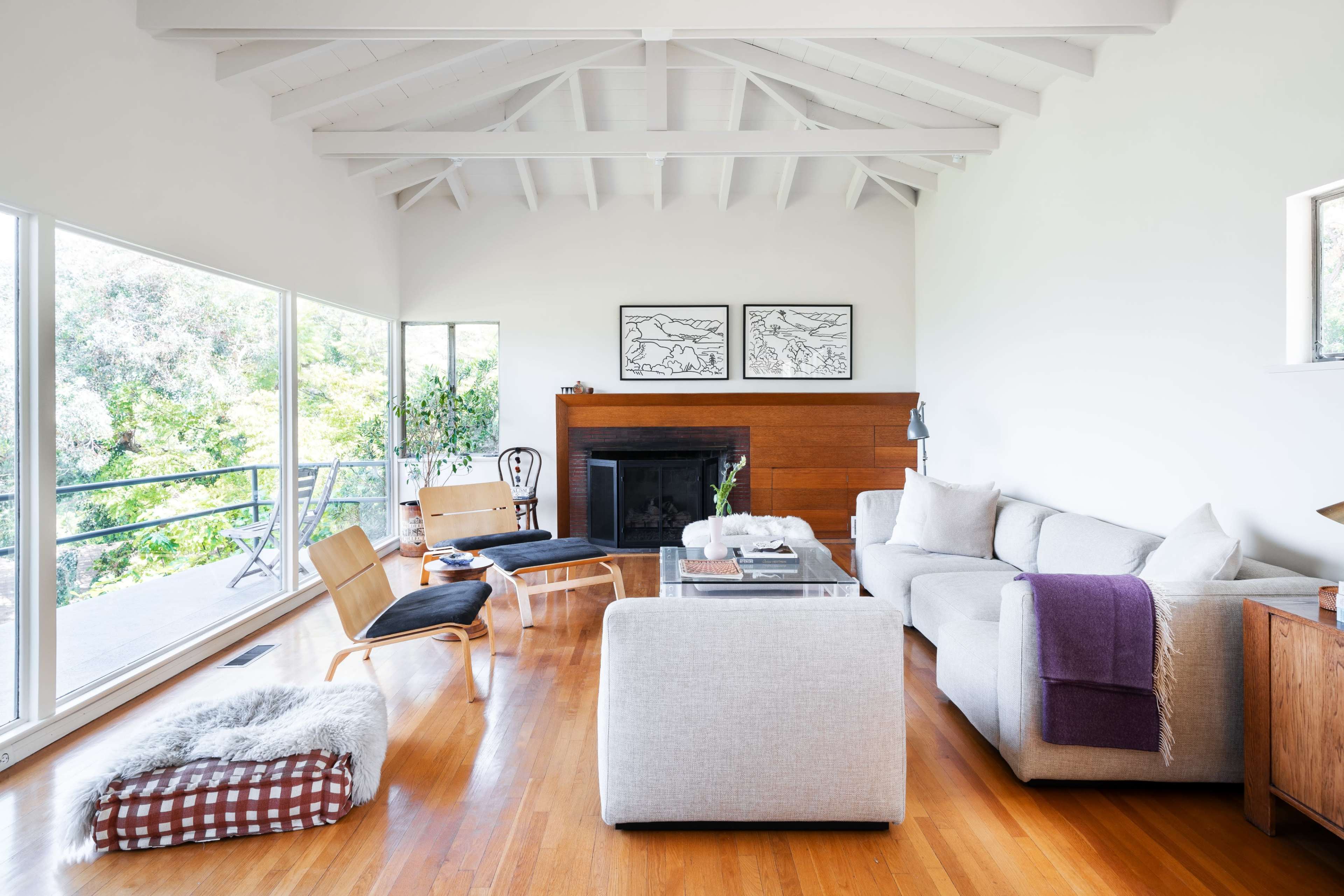 A modern living room features a light-colored sofa, wooden accents, and large windows that provide a view of the outdoors.