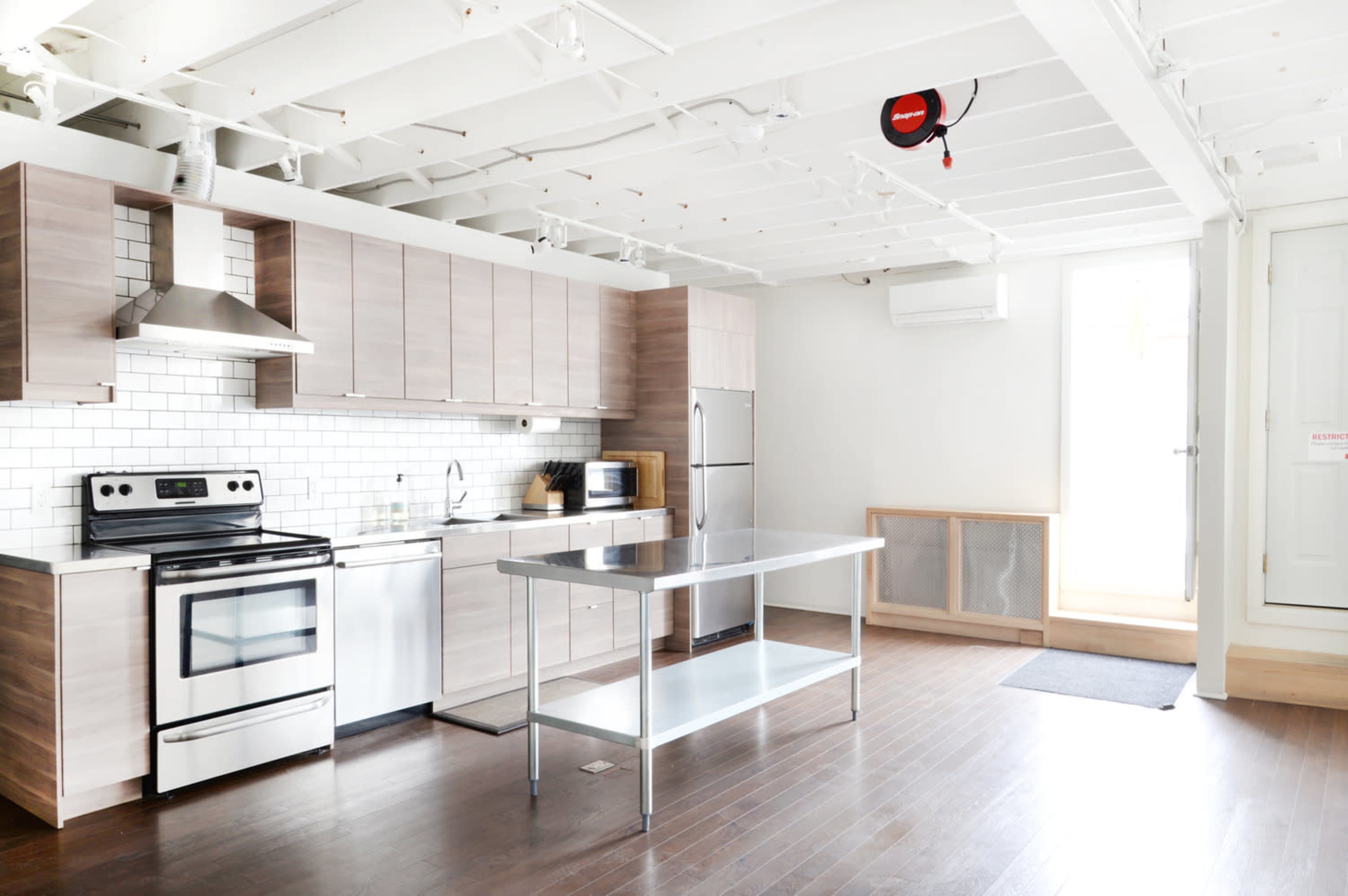 A modern kitchen with stainless steel appliances, wood cabinetry, and a central island.