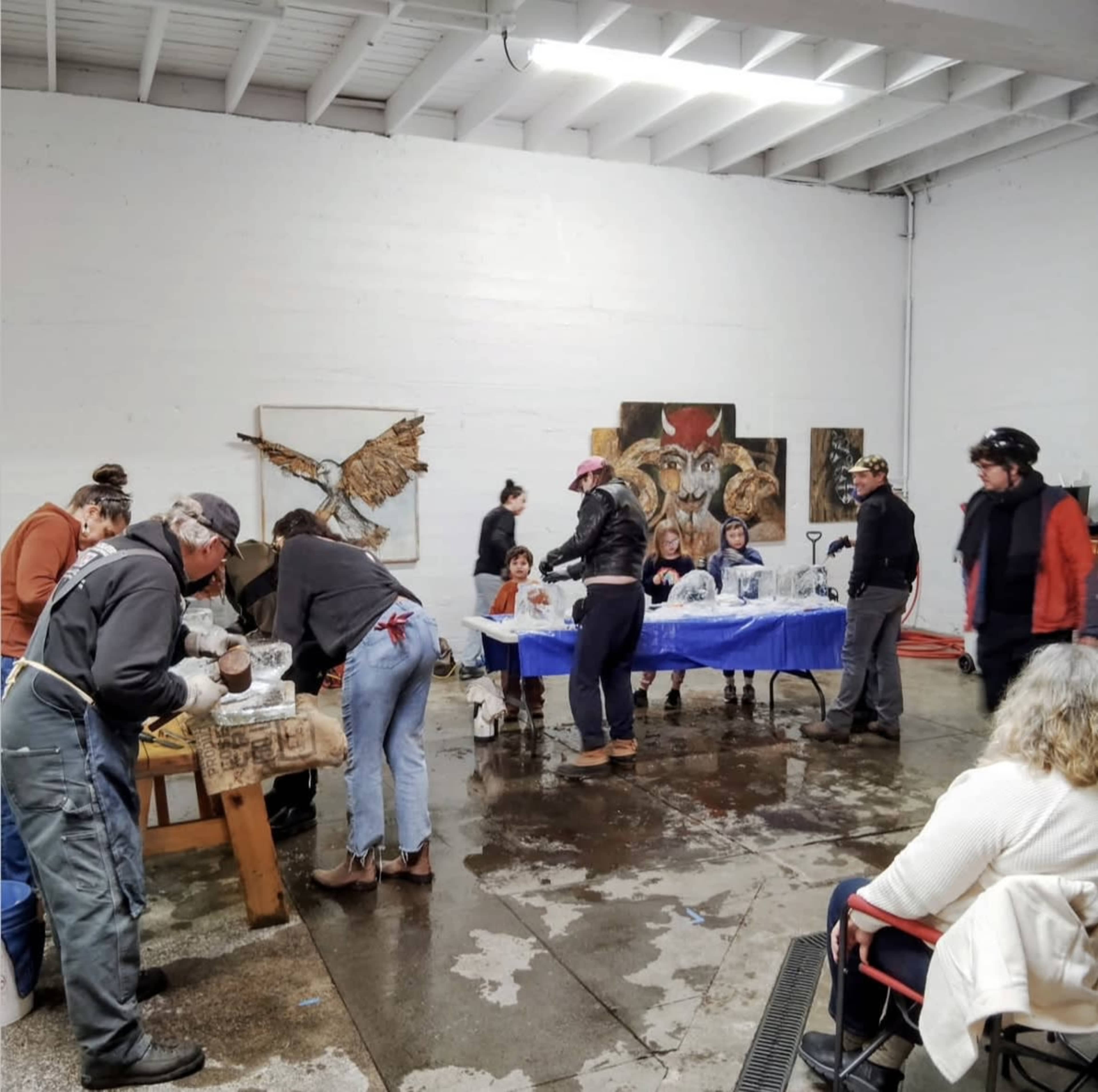 A group of people is engaged in an art workshop while working on sculptures at a studio with artwork on the walls.