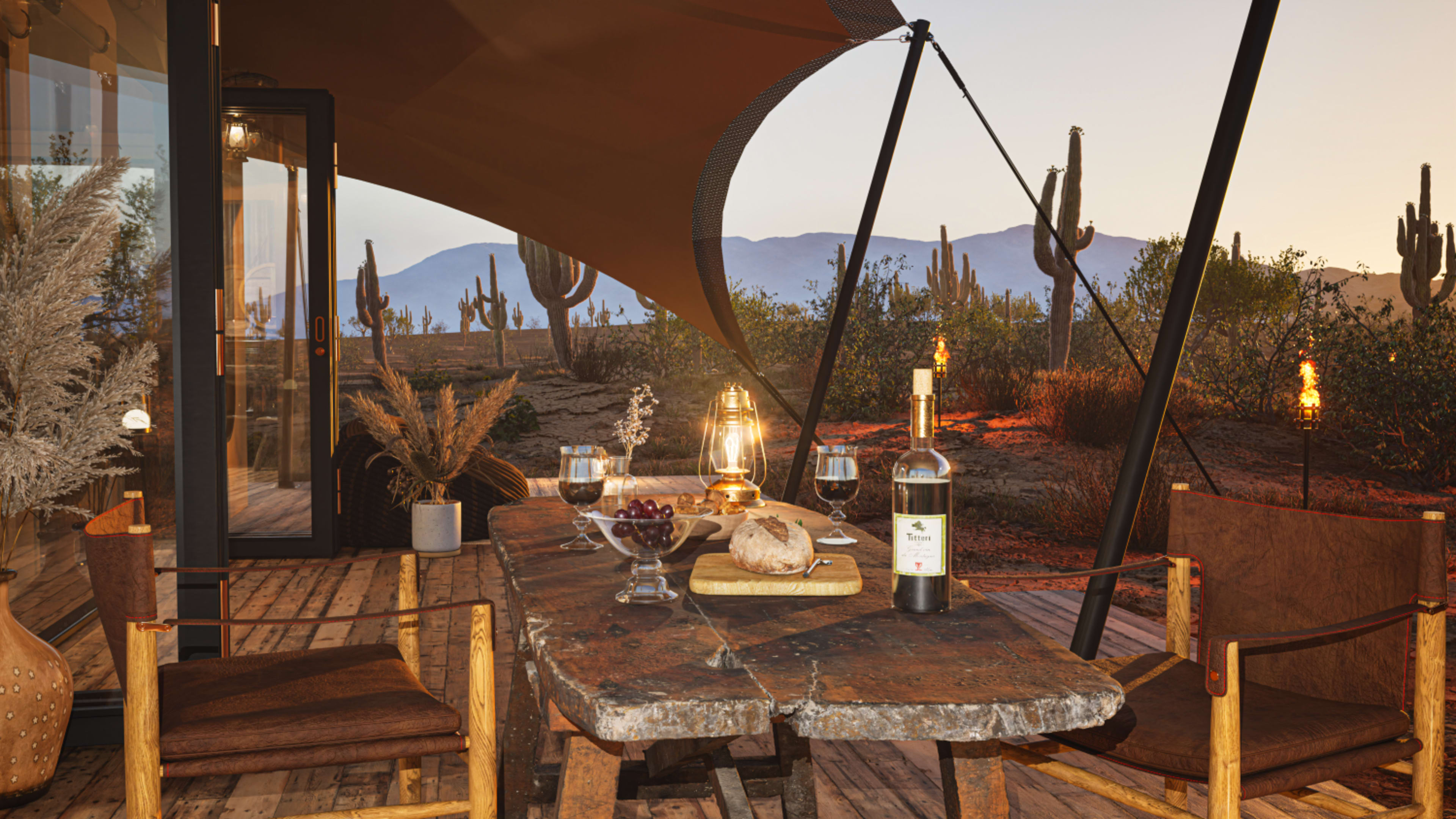 A rustic wooden table is set with a bottle of wine, glasses, and bread, under a canopy with desert landscape and cacti in the background.
