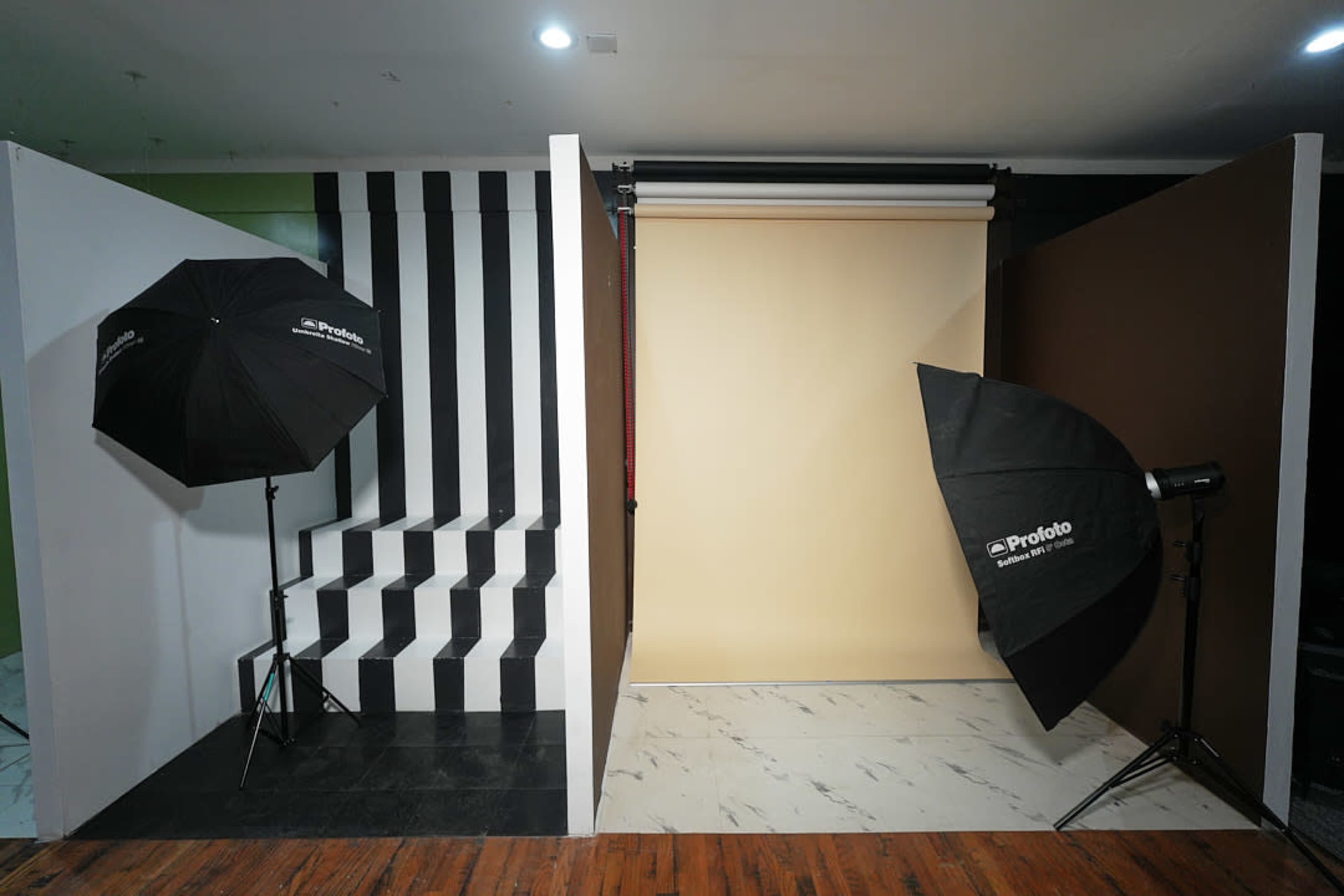 The image shows a photography studio setup featuring a striped backdrop, a solid colored backdrop, and two softbox lights positioned on either side.