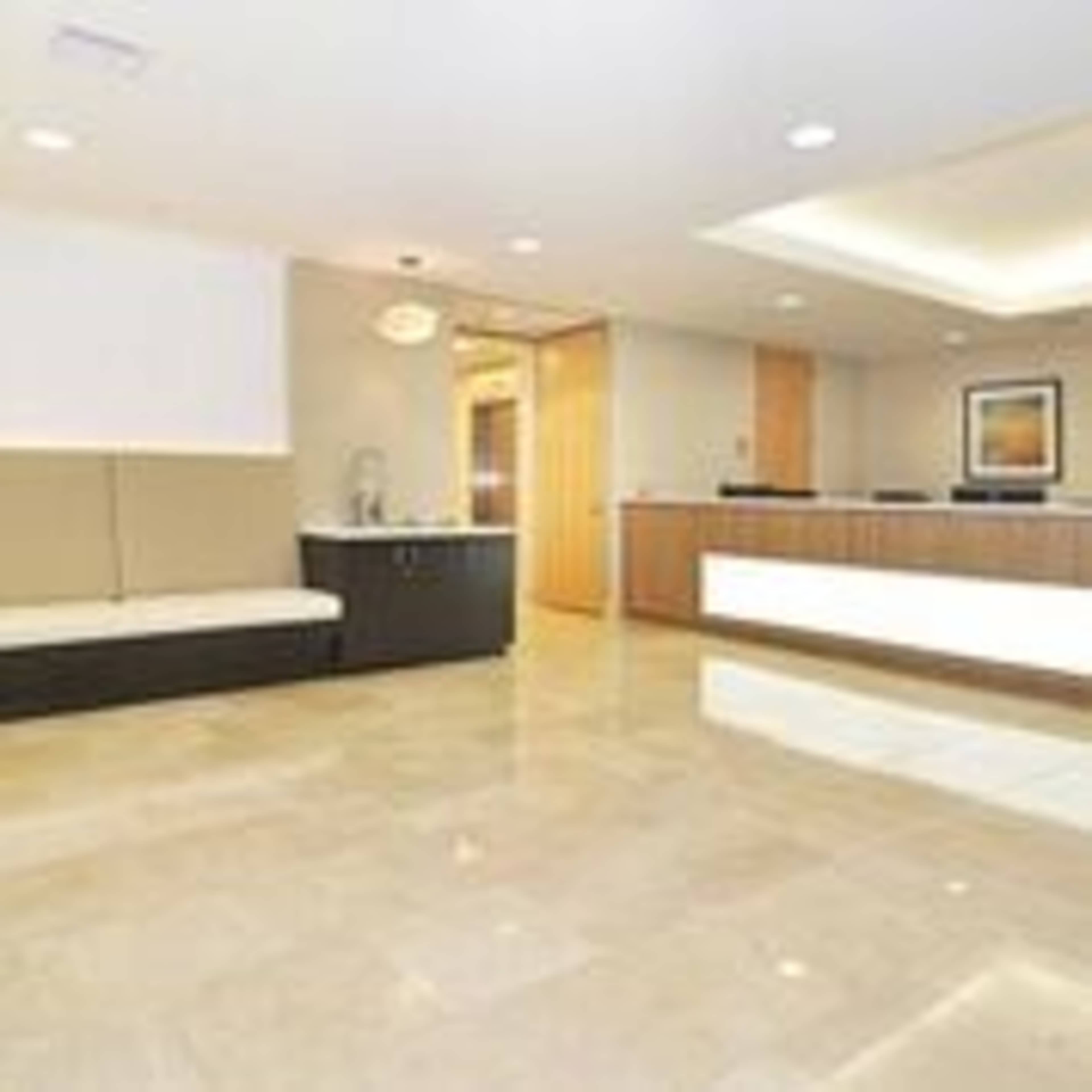 A modern reception area with a seating bench and a front desk in a well-lit office space.