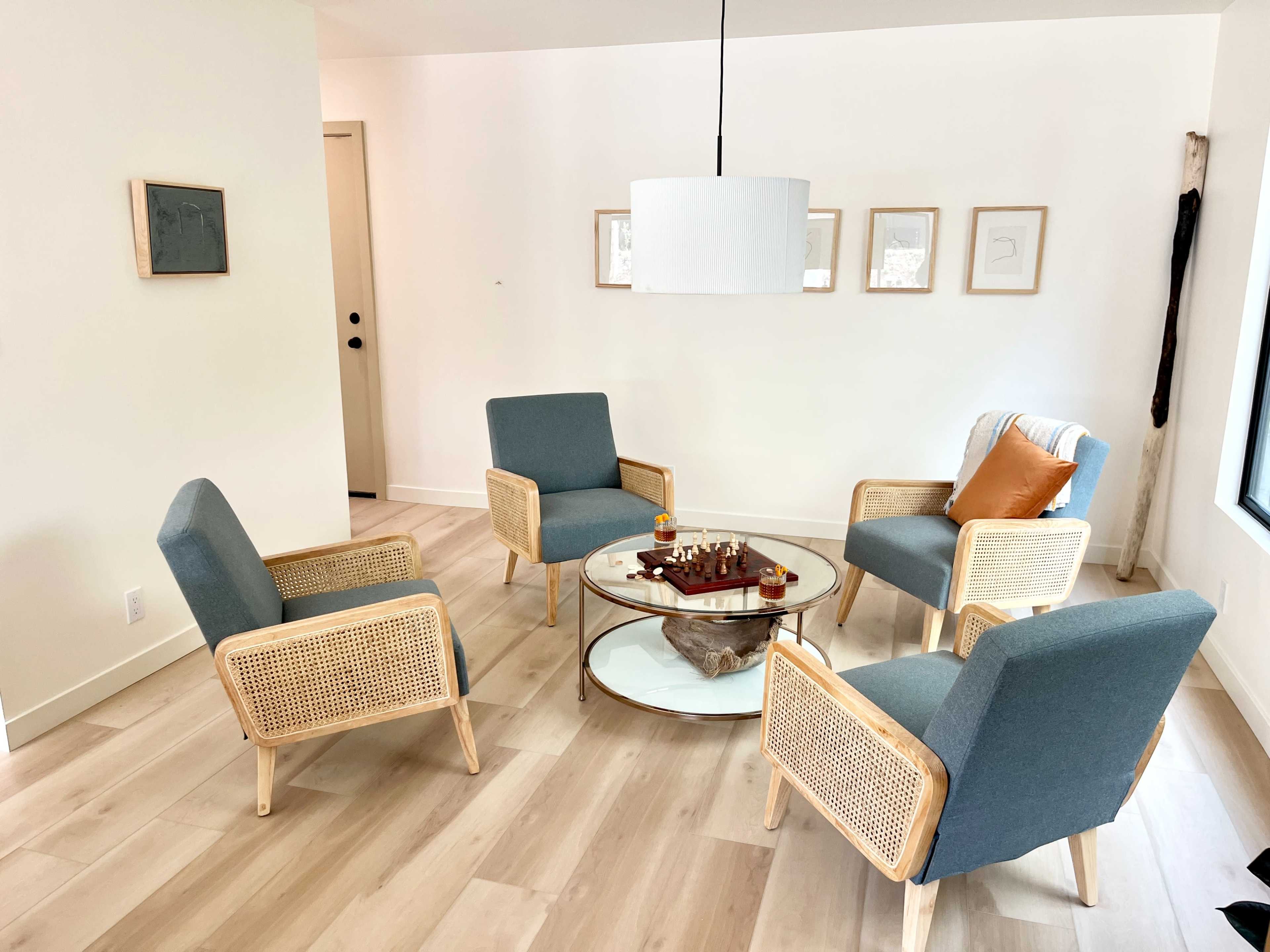 A light and airy living room features four upholstered chairs arranged around a circular coffee table.