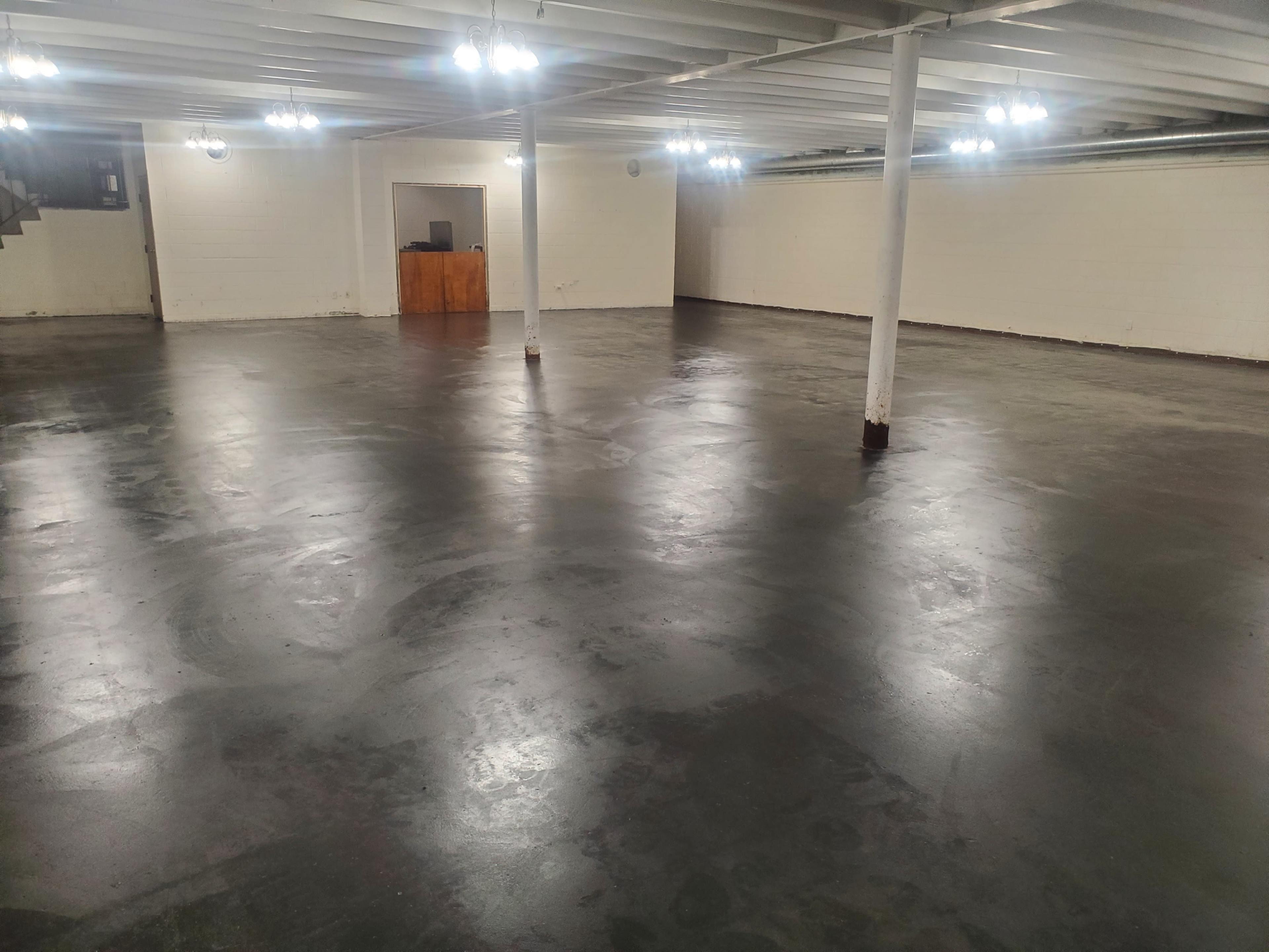 A large, empty basement with polished concrete floors and overhead lighting.