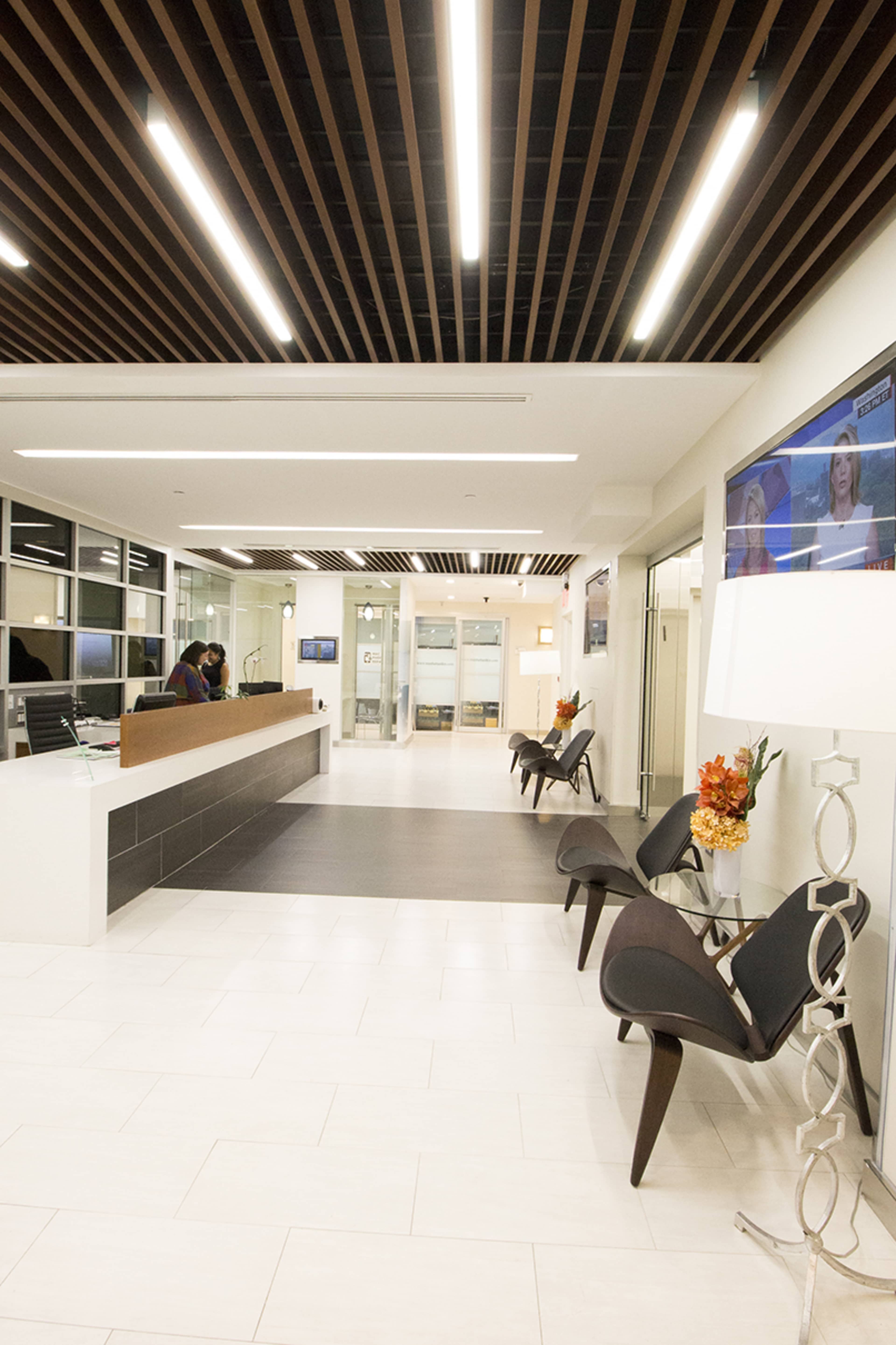 A modern reception area with a front desk, seating, and glass doors leading to another space.