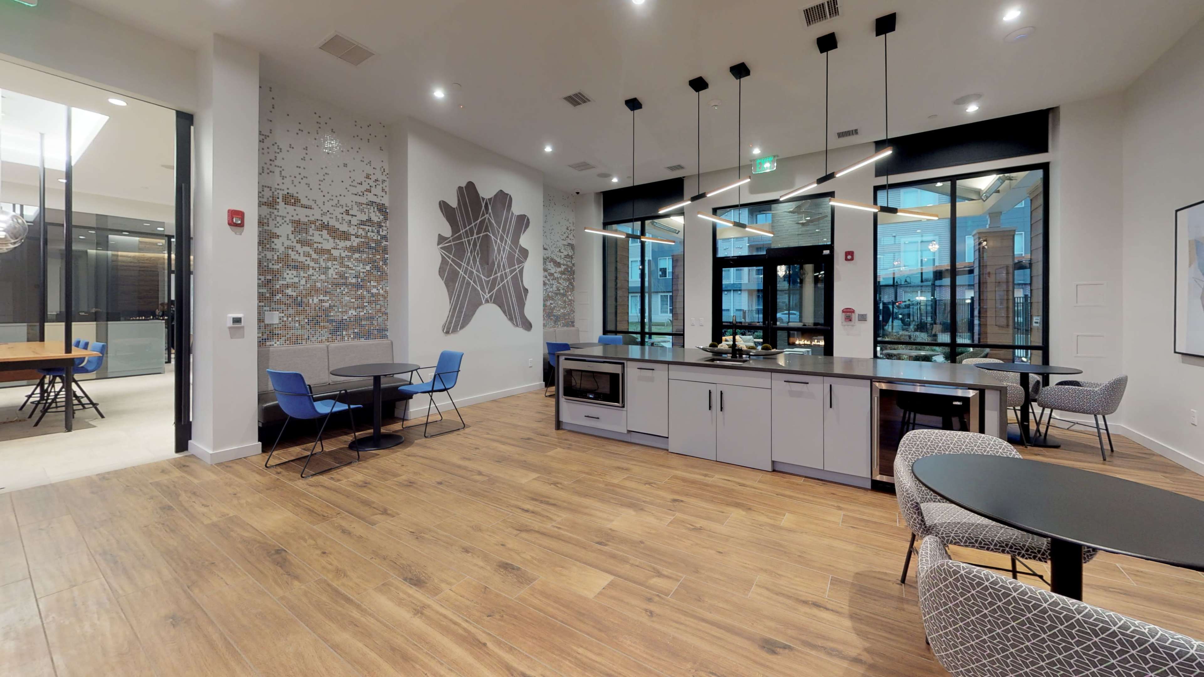 A modern communal space with kitchen amenities, seating areas, and large windows.