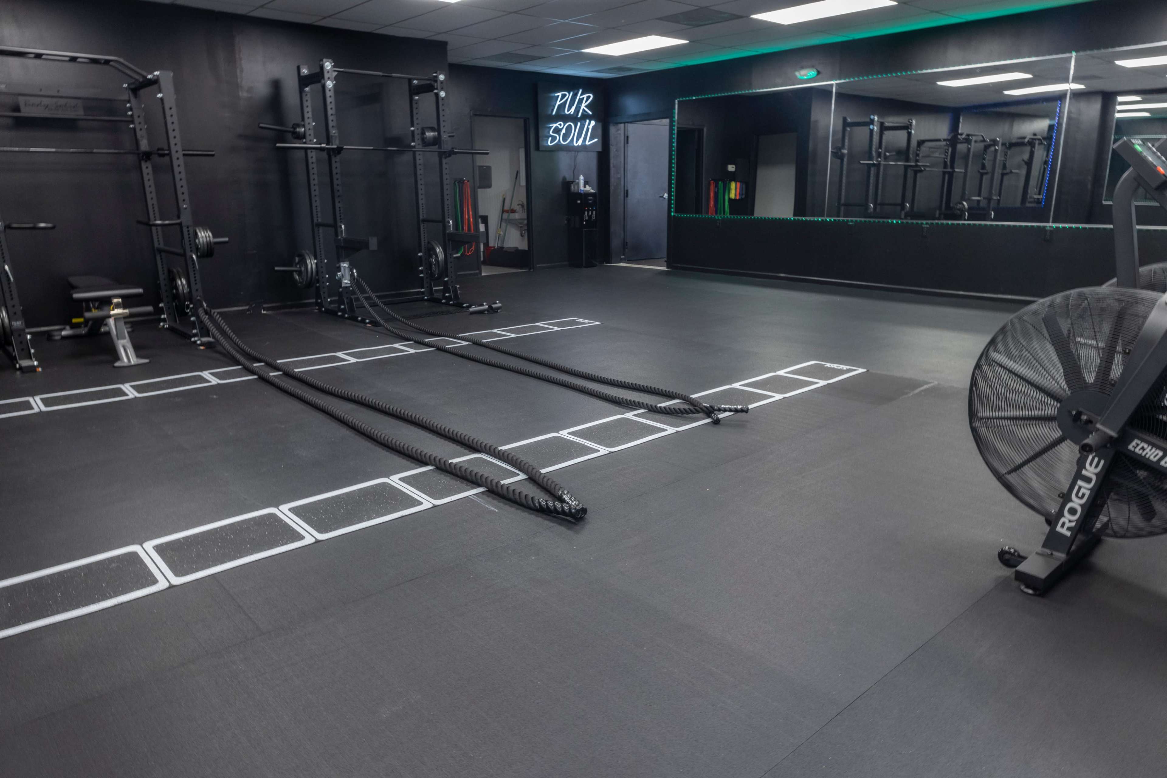 An indoor gym with exercise equipment, including ropes on the floor and a large fan in the corner.