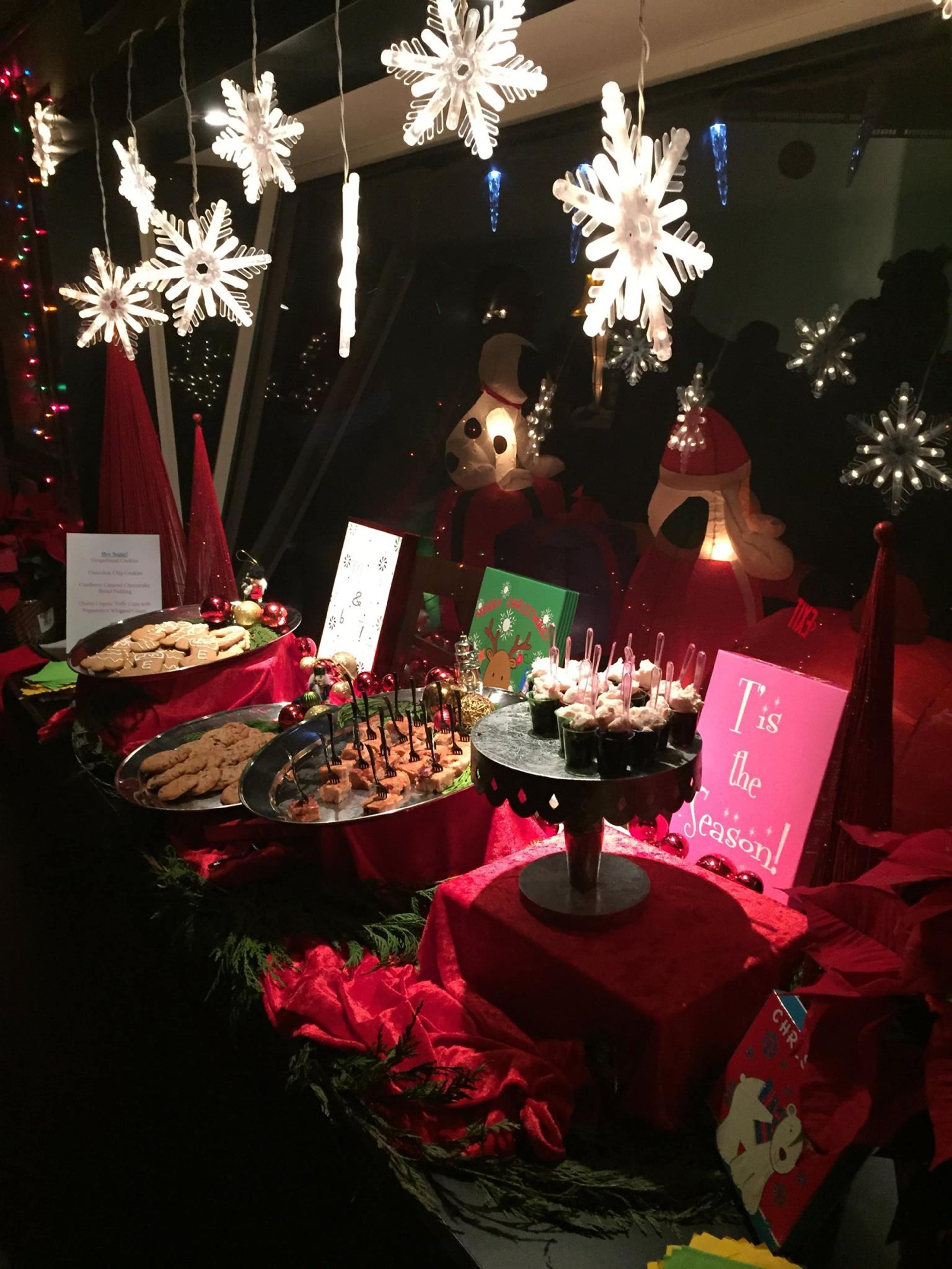 A festive table displays an array of holiday treats surrounded by decorations, including snowflakes and red foliage.
