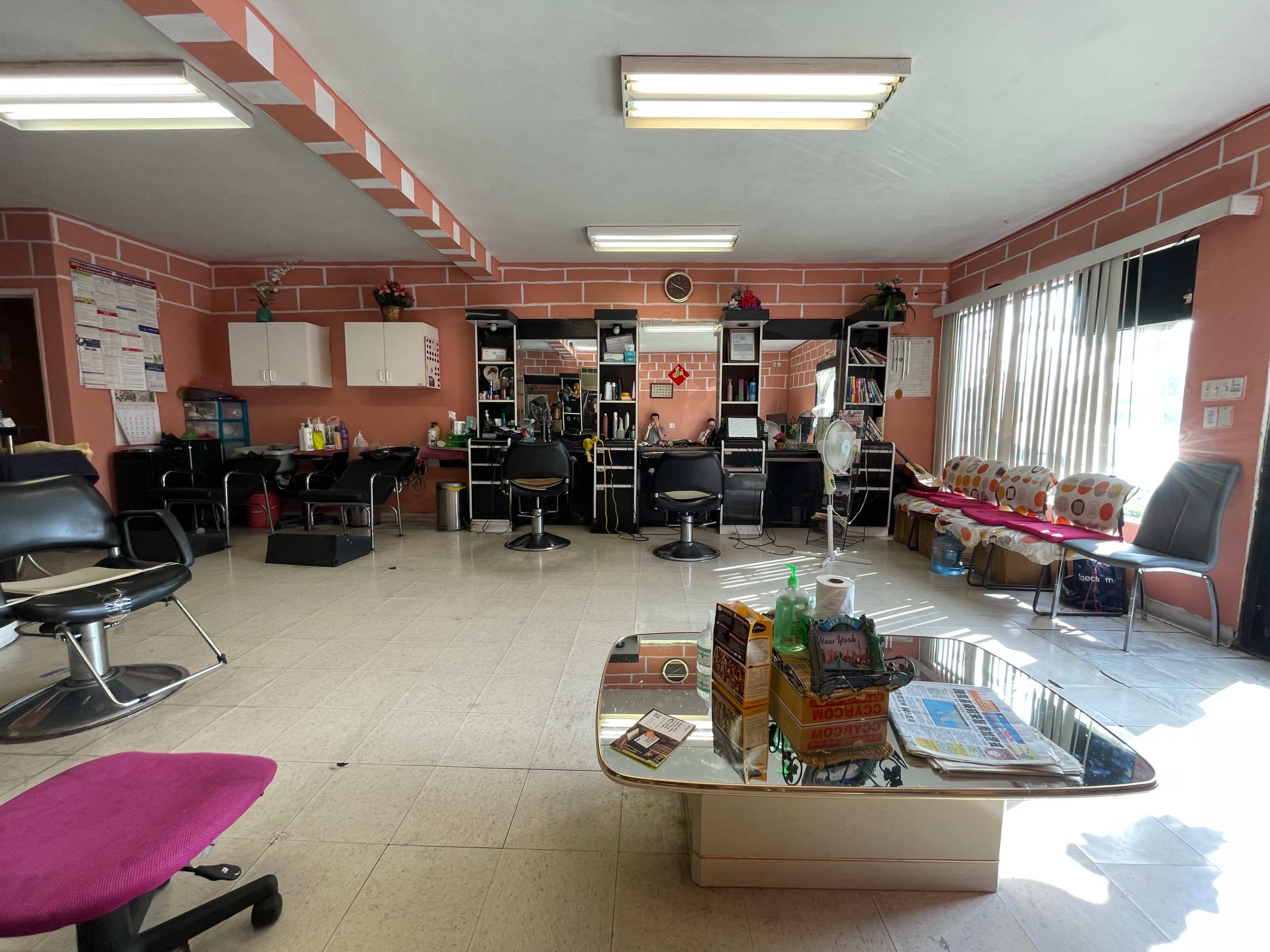 The interior of a hair salon with several styling stations, a coffee table, and a waiting area.