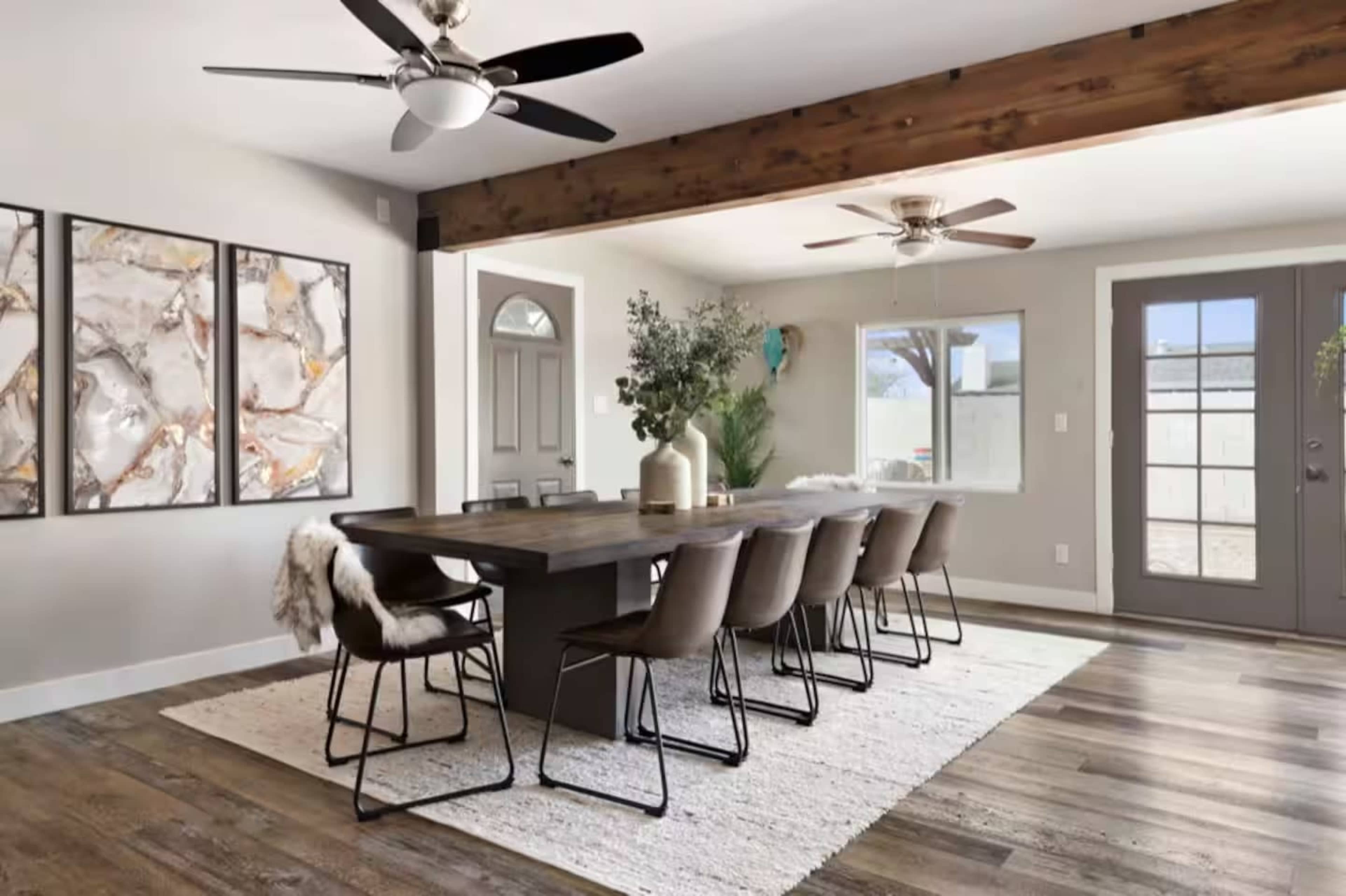 The image depicts a modern dining room with a large table, eight chairs, and two ceiling fans, featuring a combination of wood and neutral tones.