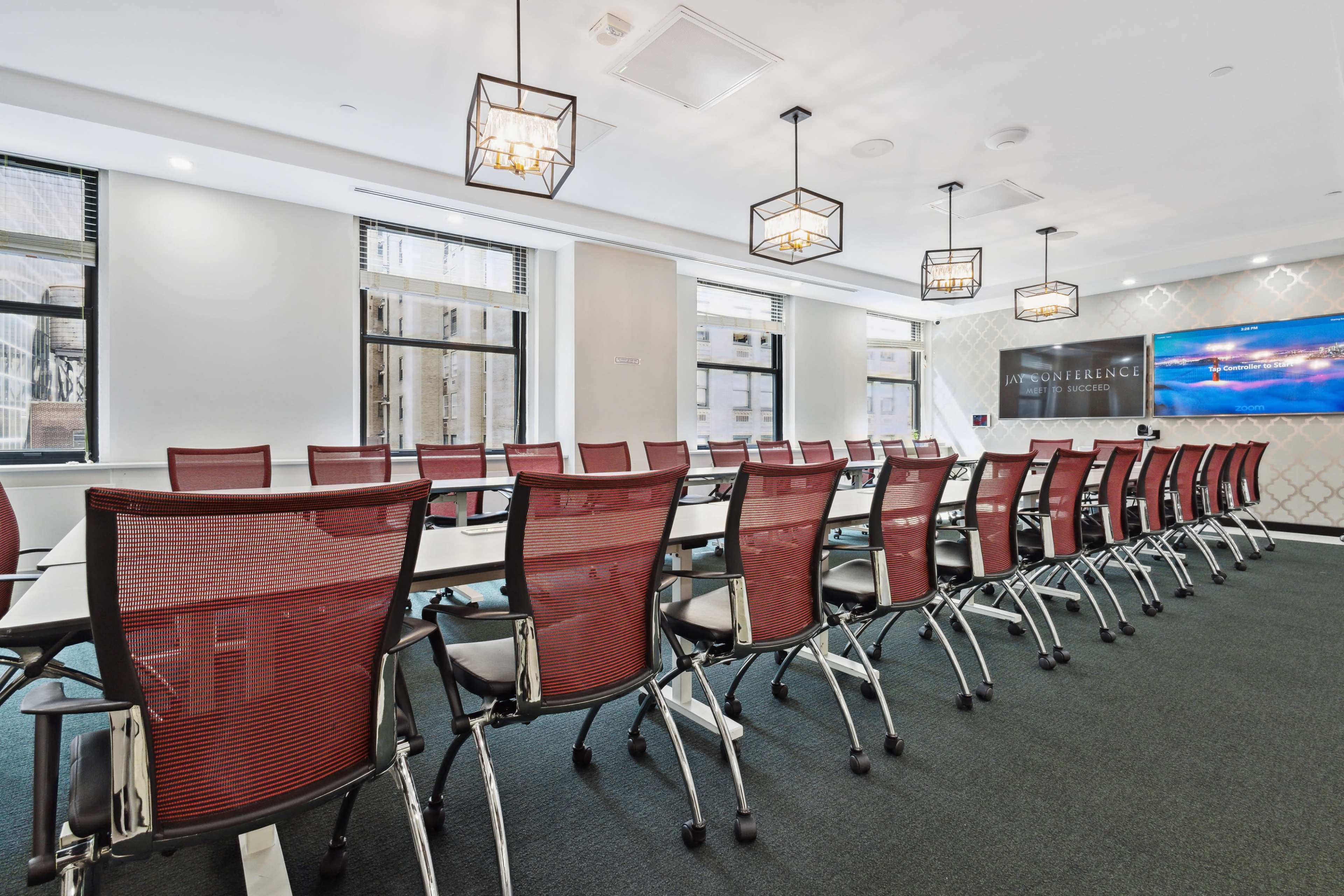 A modern conference room features a long table with ergonomic chairs and large windows allowing natural light.