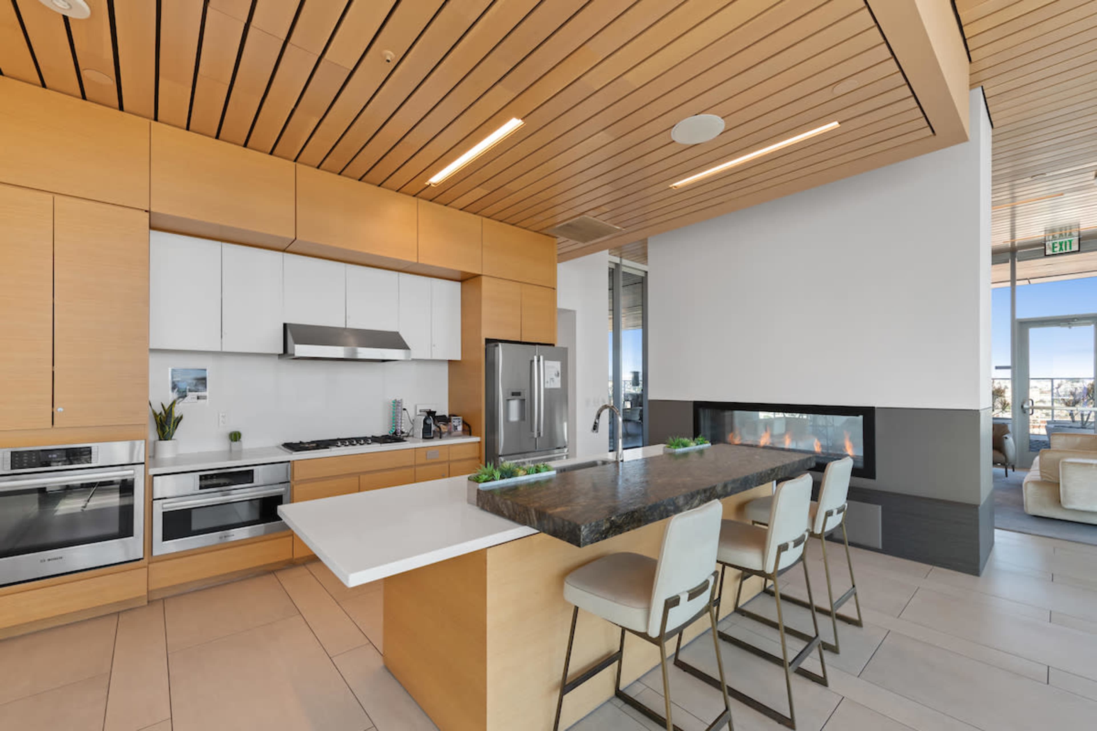 A modern kitchen with wooden cabinetry, stainless steel appliances, and a large island with seating.