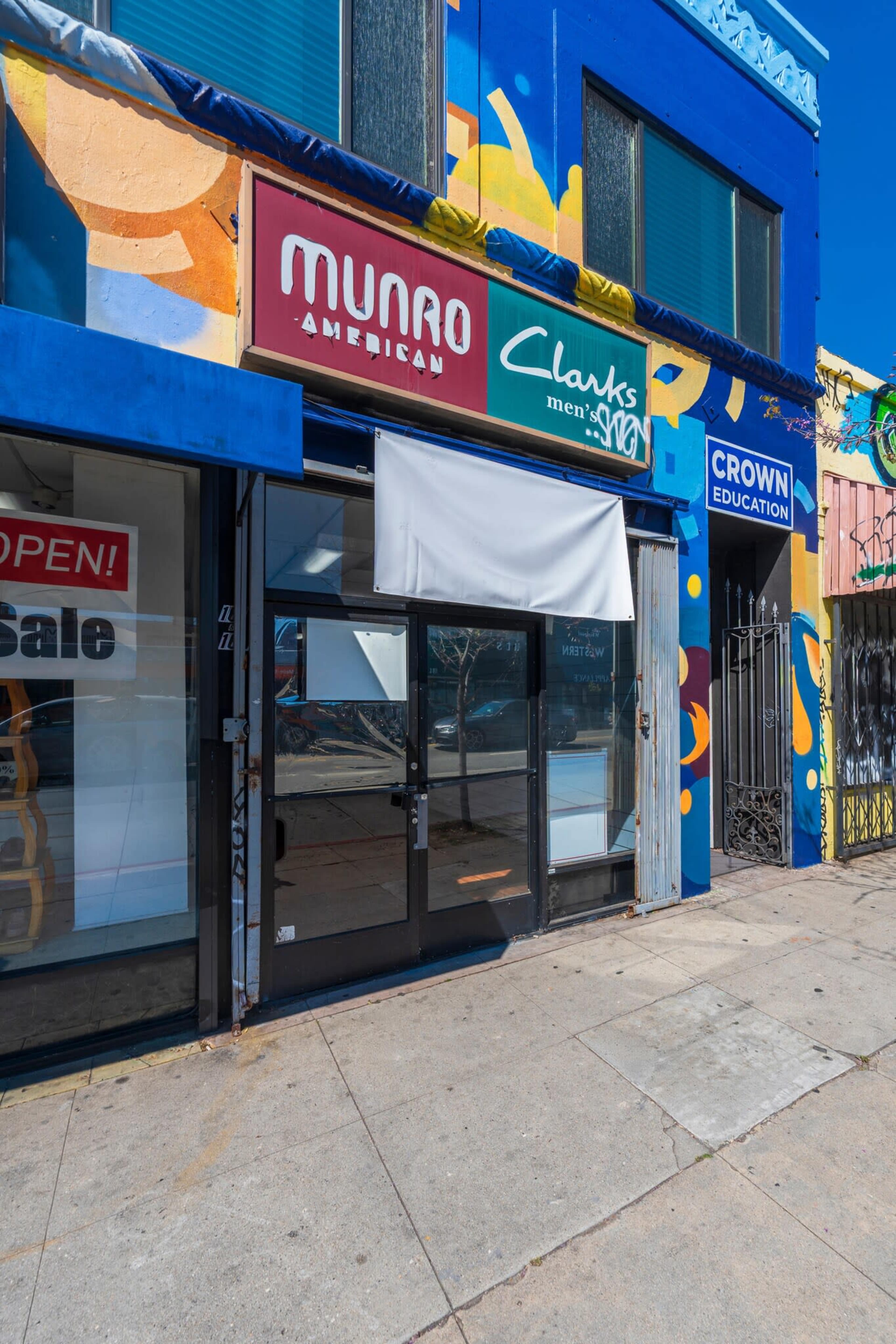 The storefront features signs for Munro American, Clarks, and Crown Education, with a white awning partially covering the entrance.
