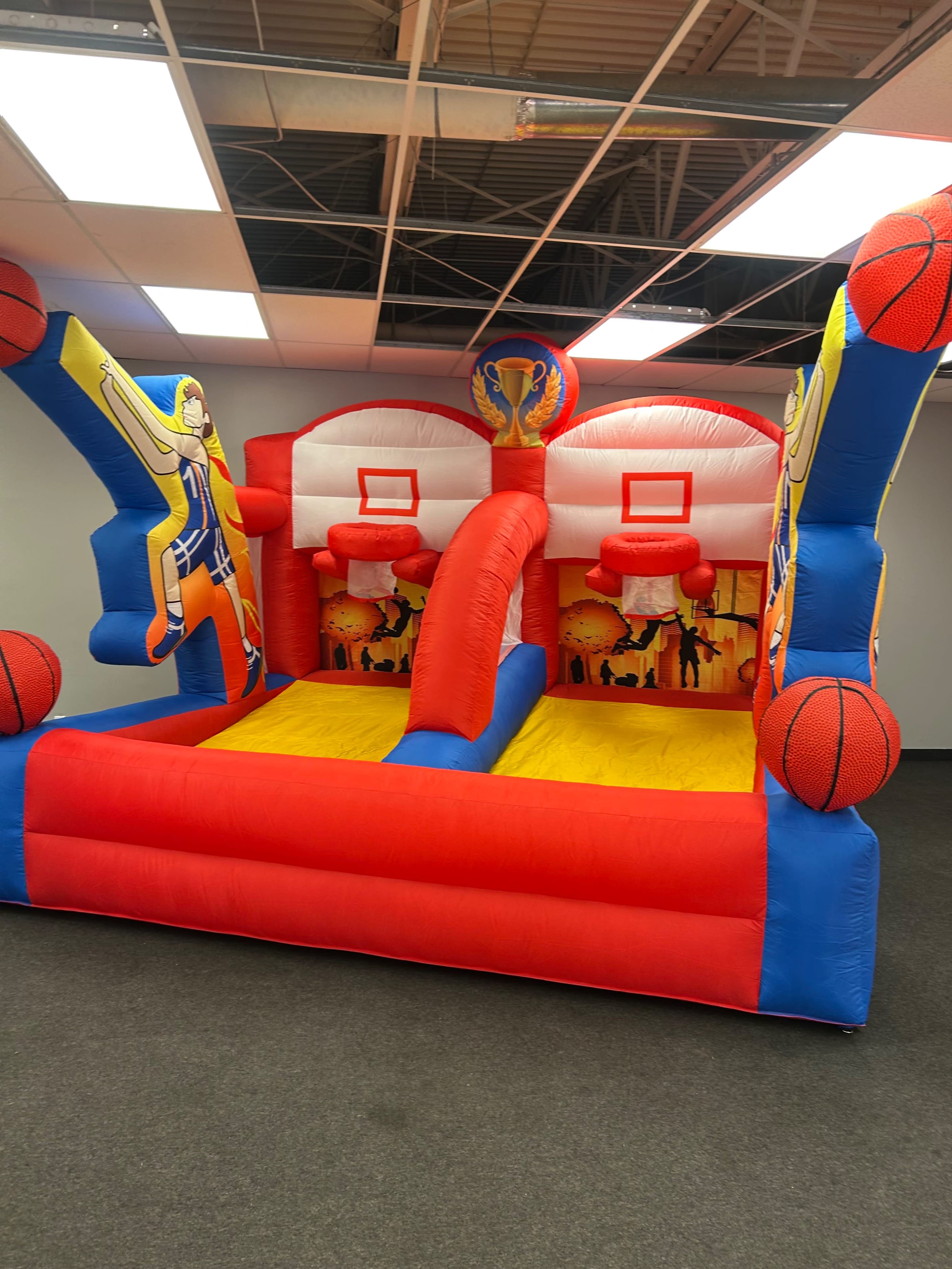 The image shows a colorful inflatable basketball game with two hoops and vibrant graphics.