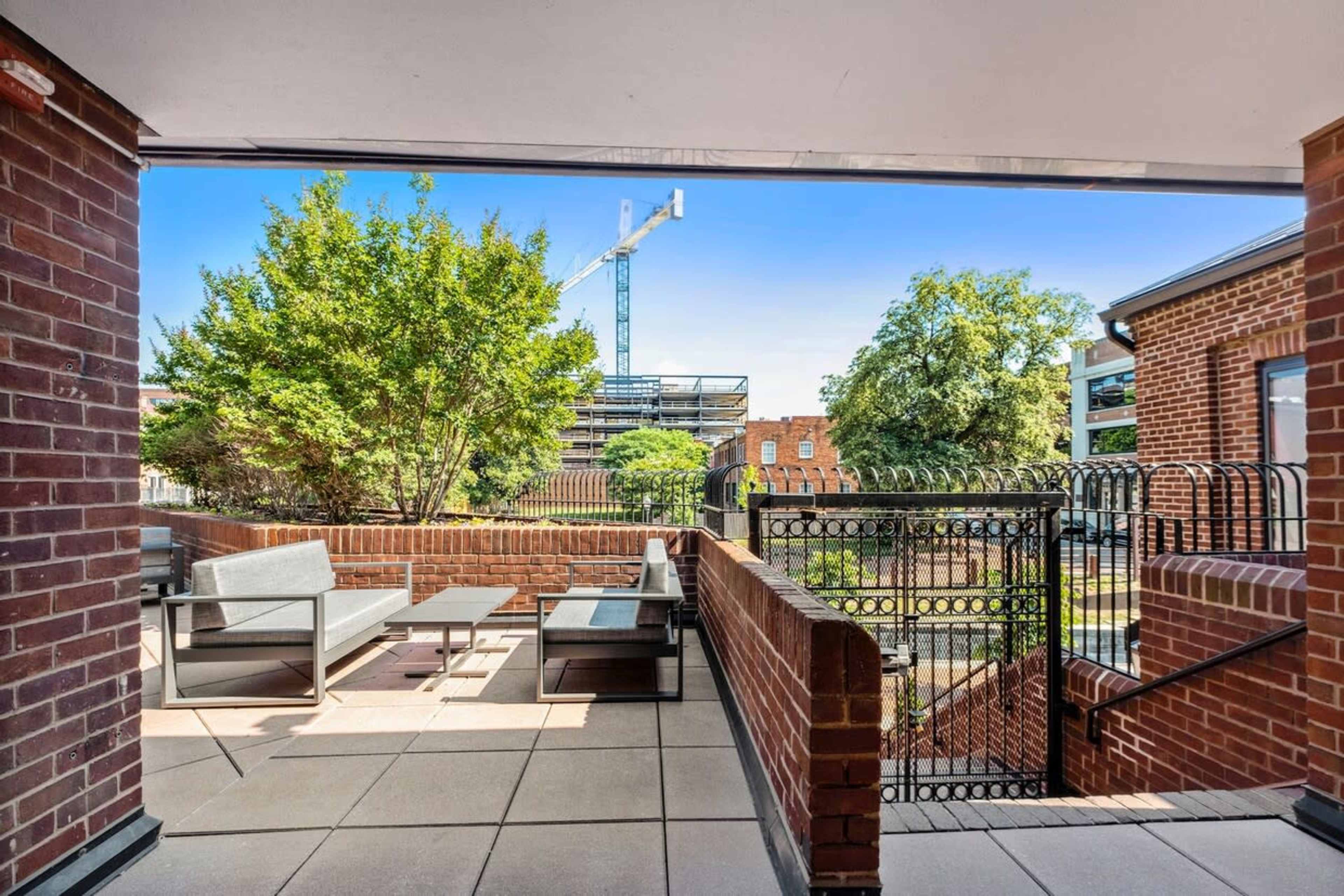 A patio features modern furniture with a view of a construction site and surrounding greenery.