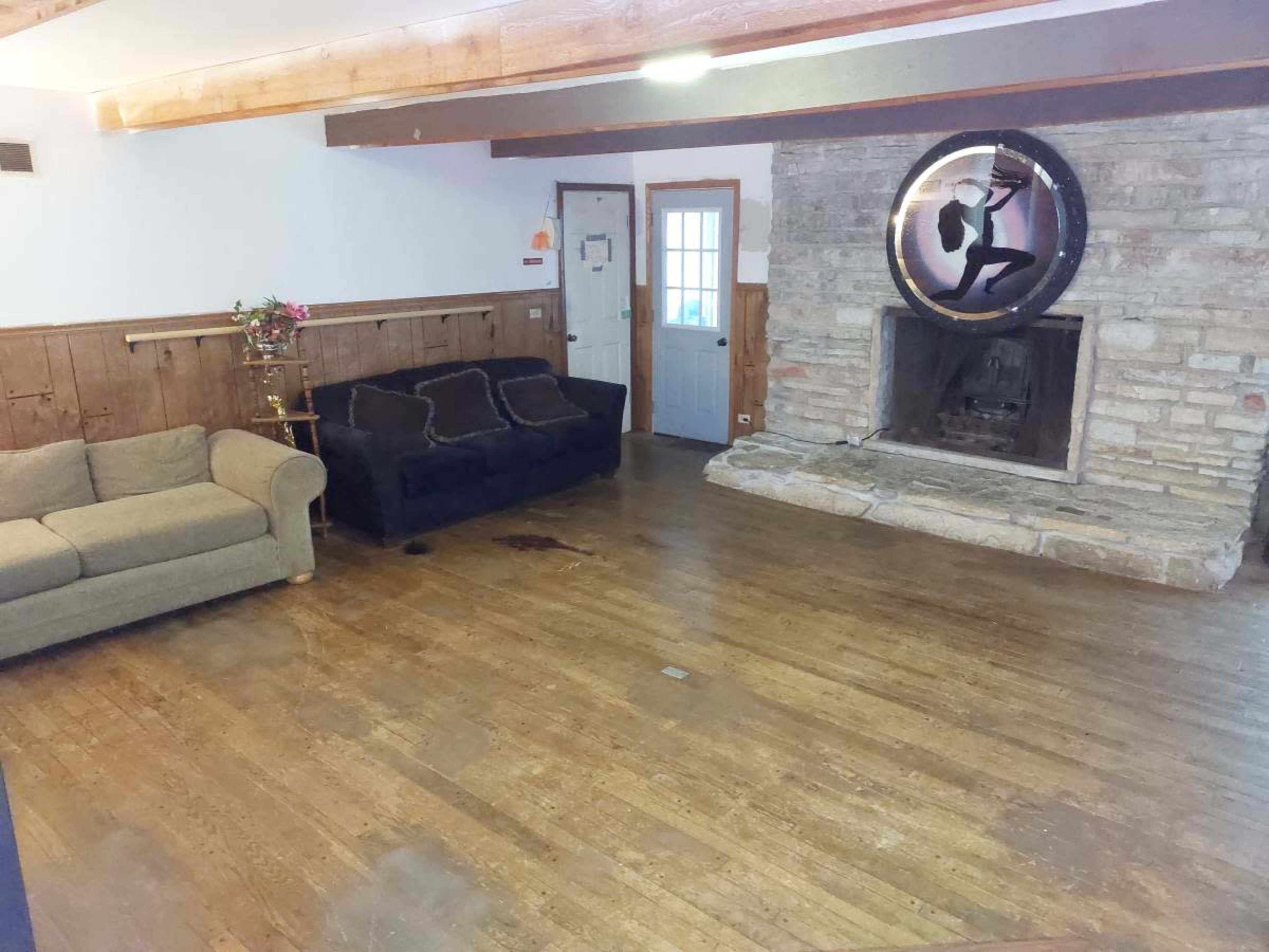 A simple living room with two sofas, a stone fireplace, and a large round mirror on the wall.
