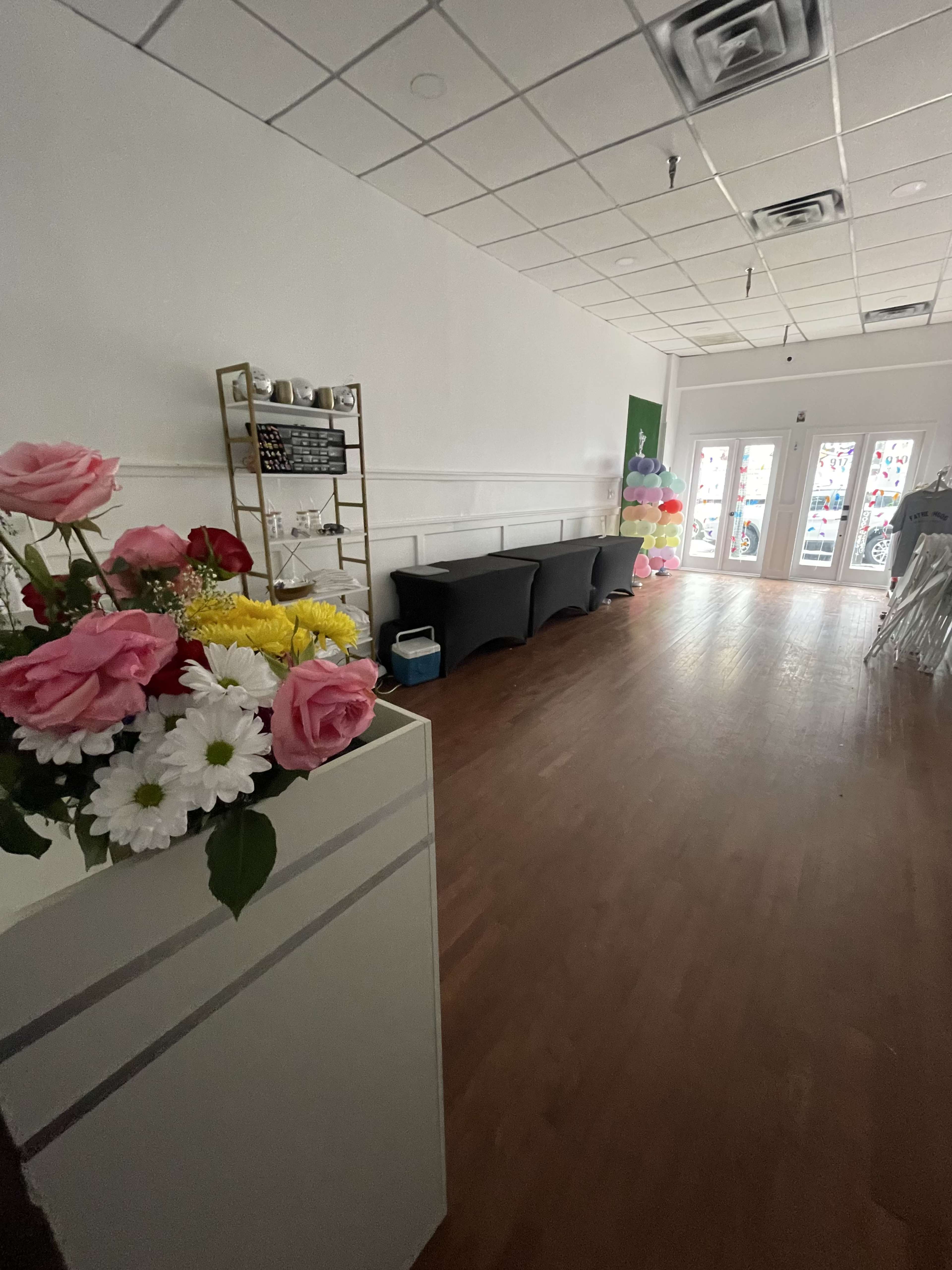 The image shows a spacious interior of a flower shop with a display of flowers in a planter and seating arrangements along one side.