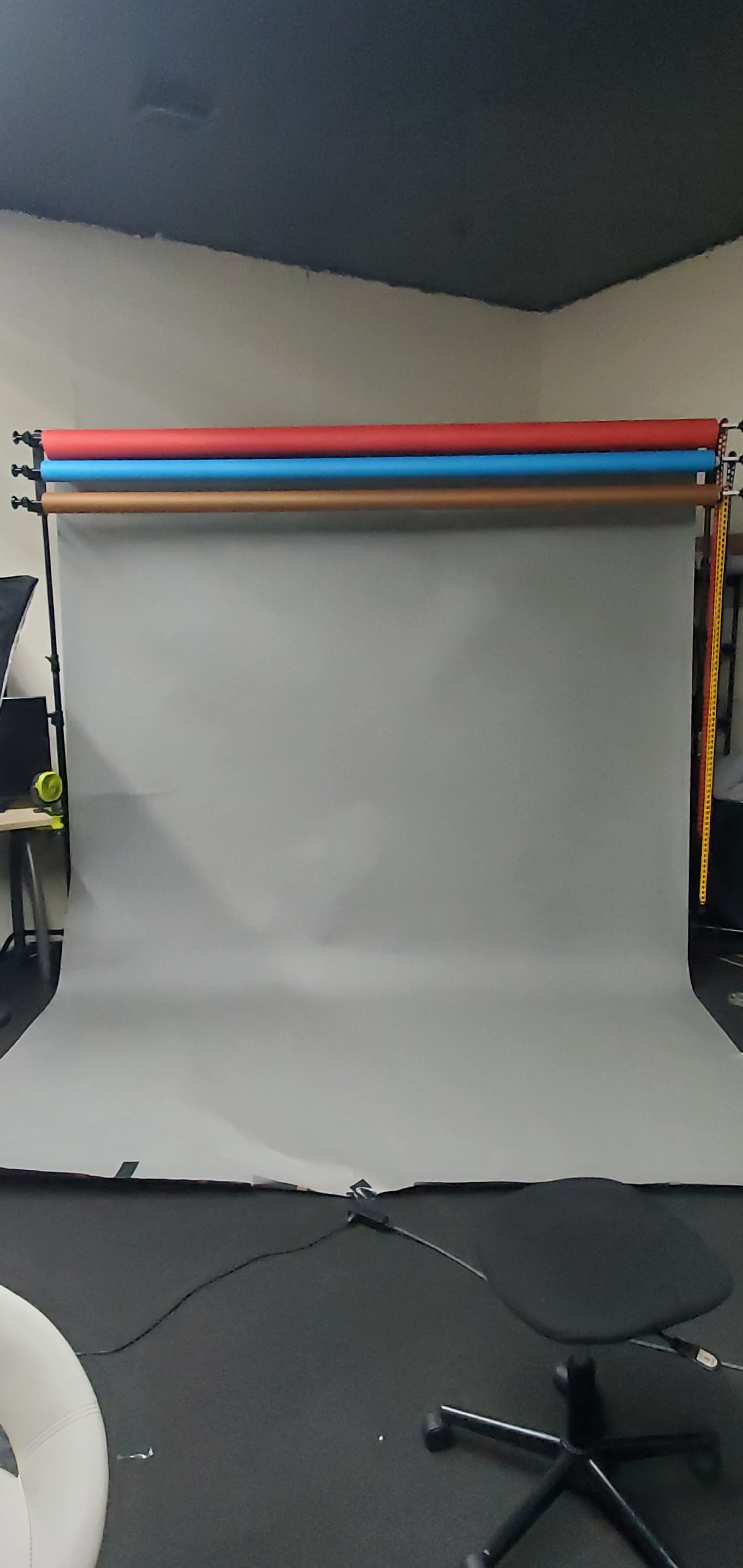 A photography backdrop setup with a gray backdrop and colorful support rods at the top.