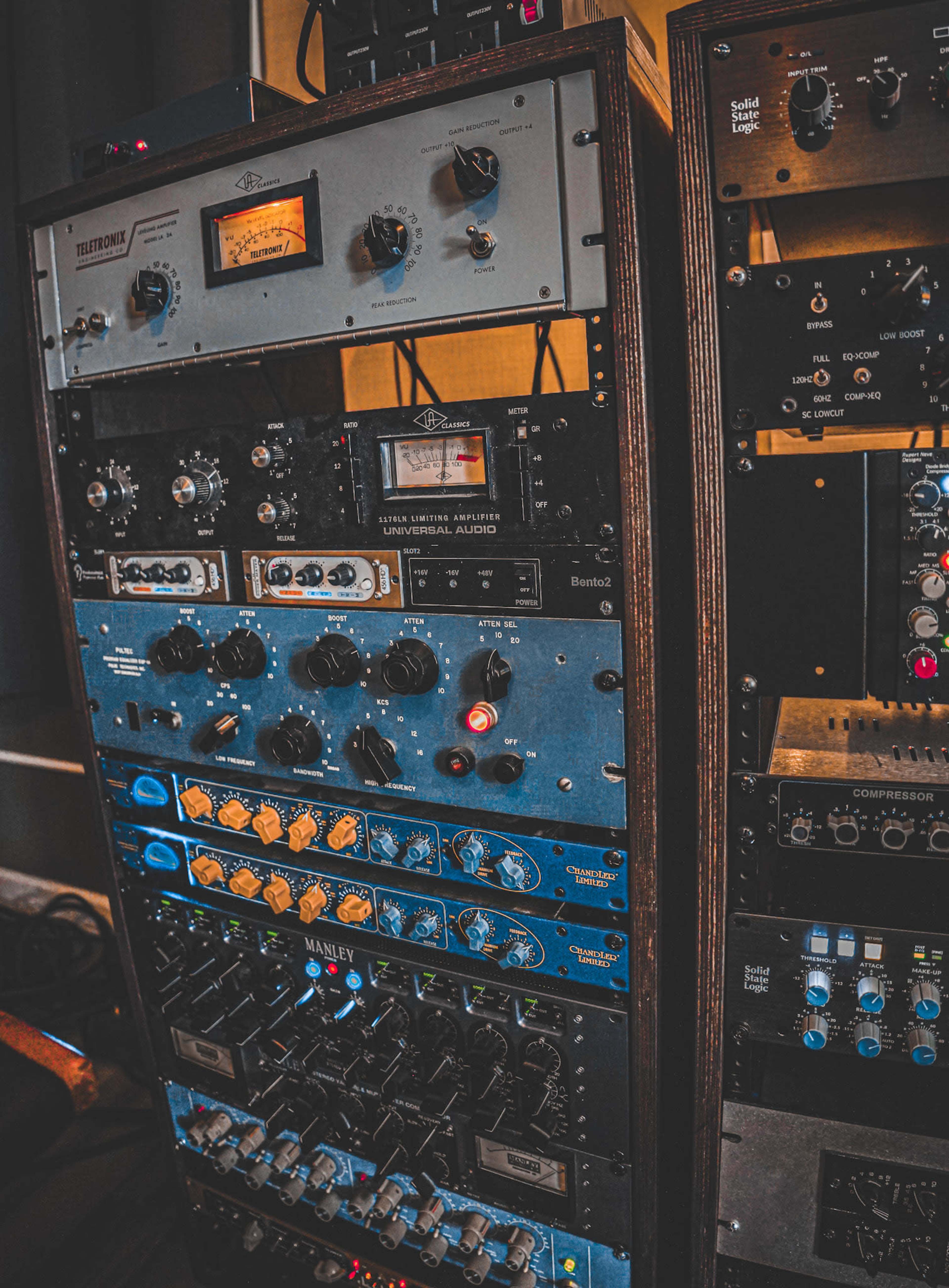 A stack of audio equipment, featuring various racks of knobs, buttons, and meters used for sound processing and mixing.