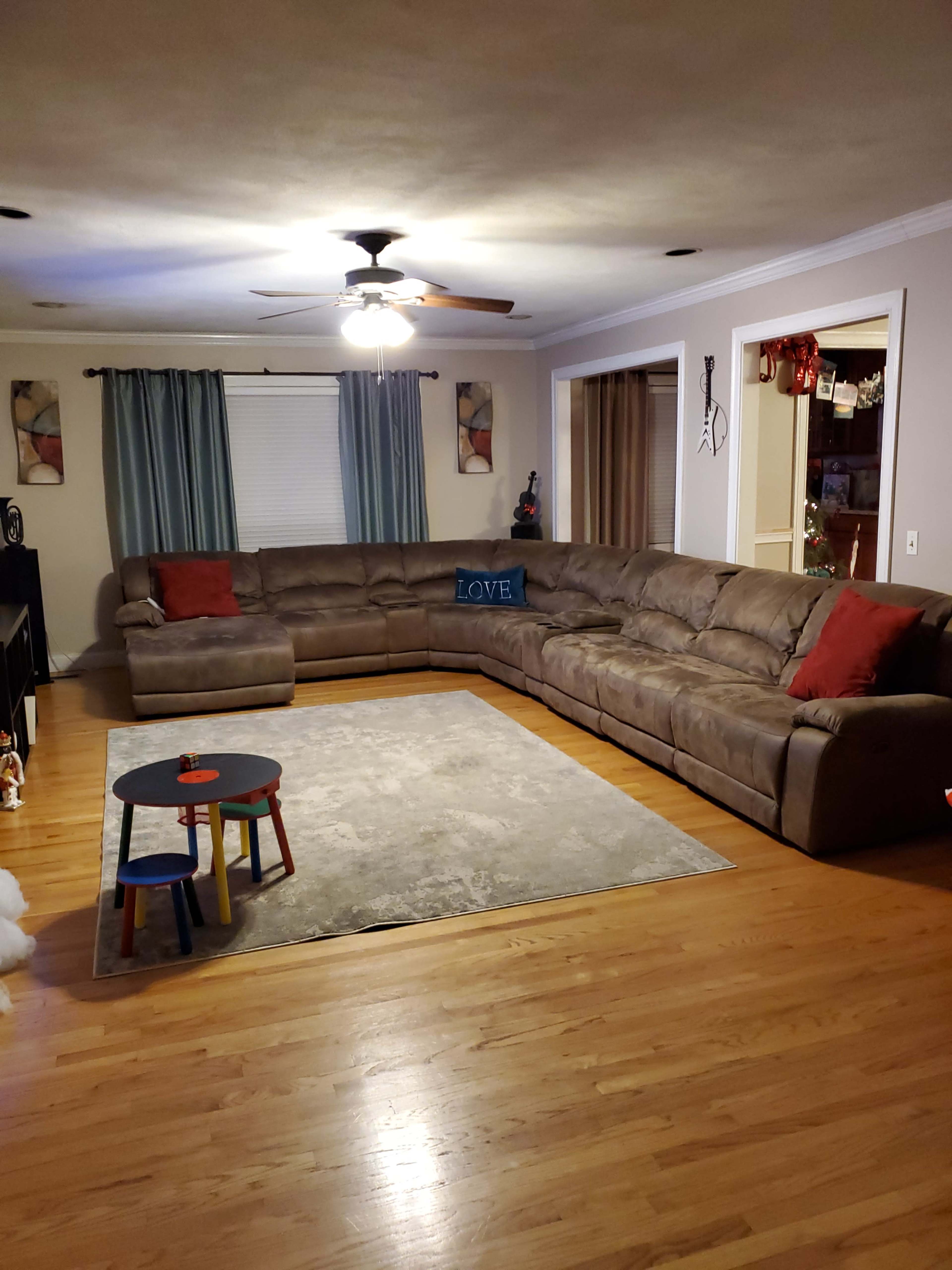 A living room with a large sectional sofa, a small round coffee table, and a rug on a hardwood floor.