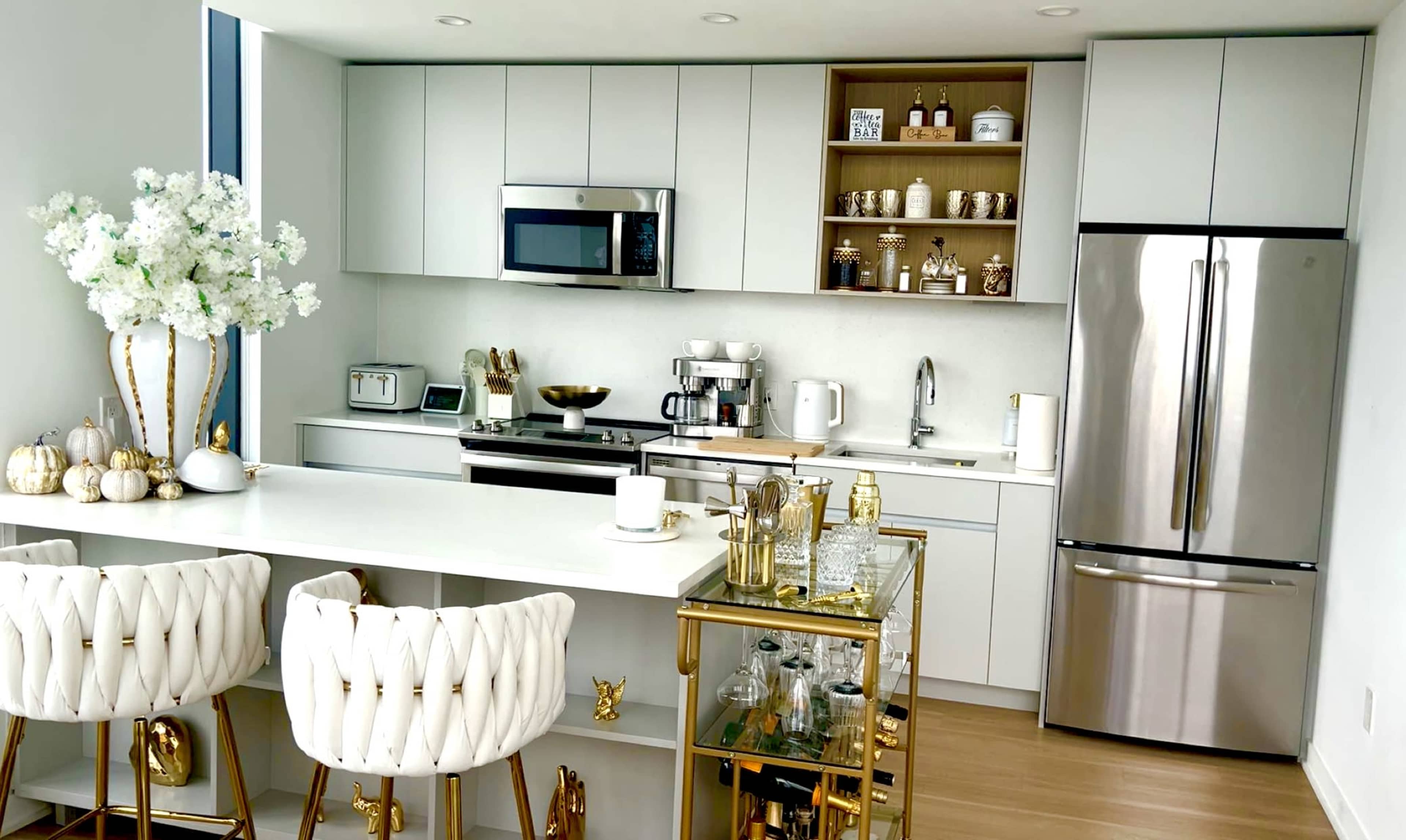 The kitchen features modern cabinetry, stainless steel appliances, and a stylish island with white bar stools and decorative accents.