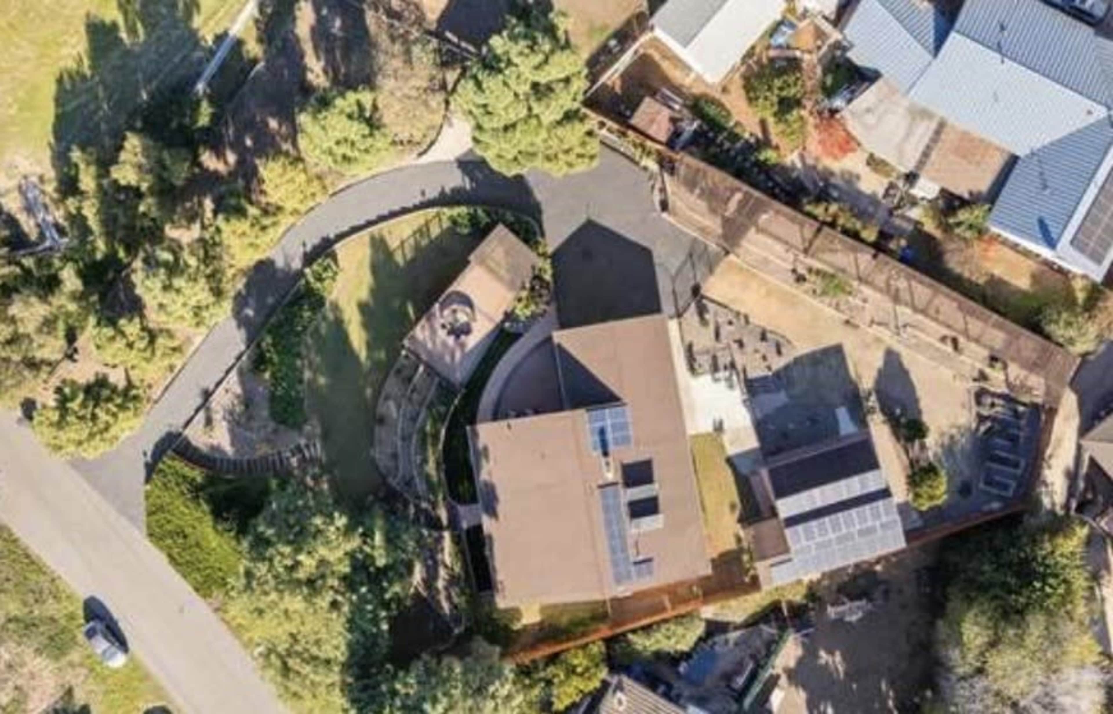 The image shows an aerial view of a residential property with multiple buildings, a circular driveway, and surrounding greenery.