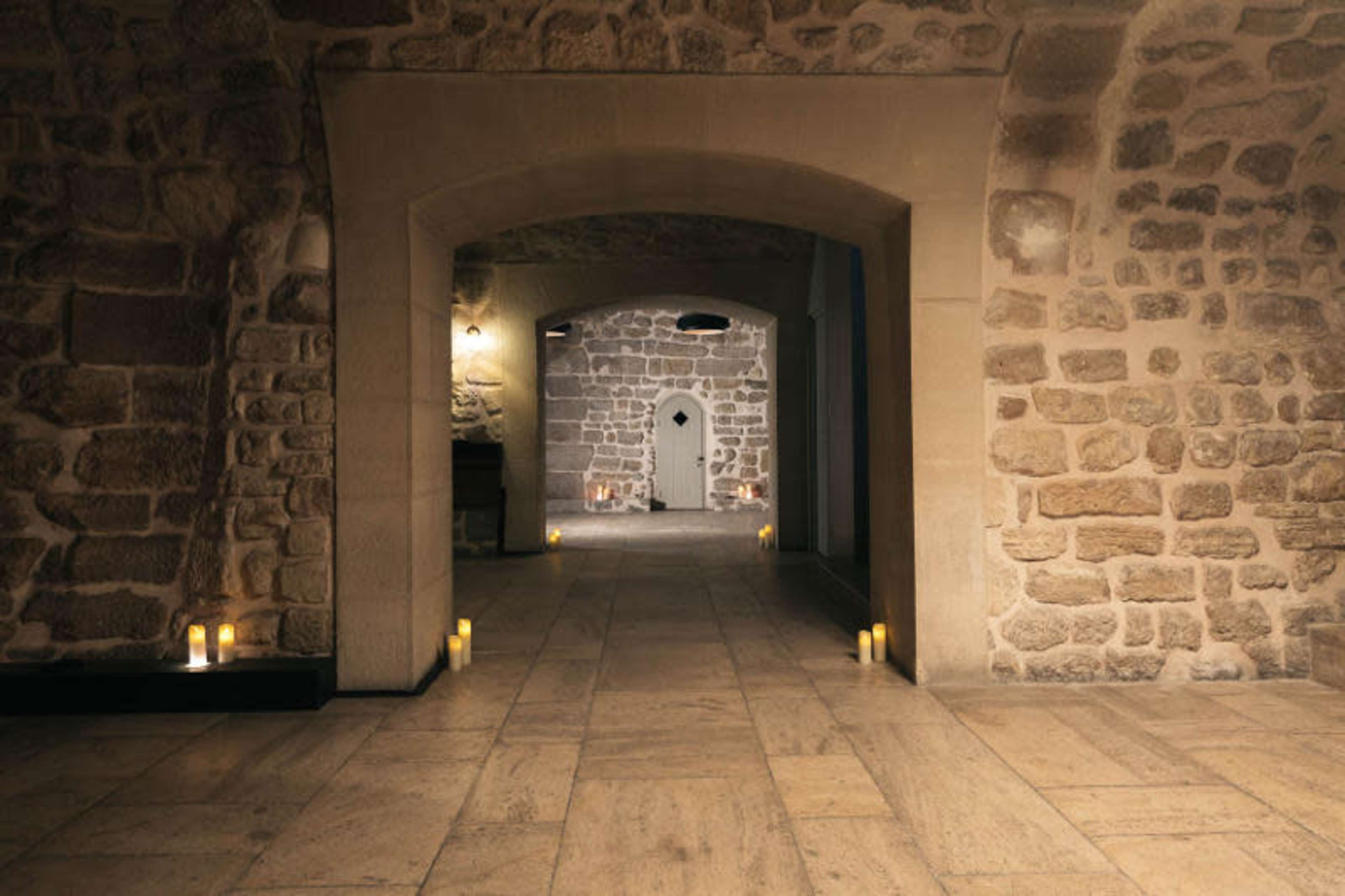 A stone-walled interior features arched doorways and candle-lit spaces.
