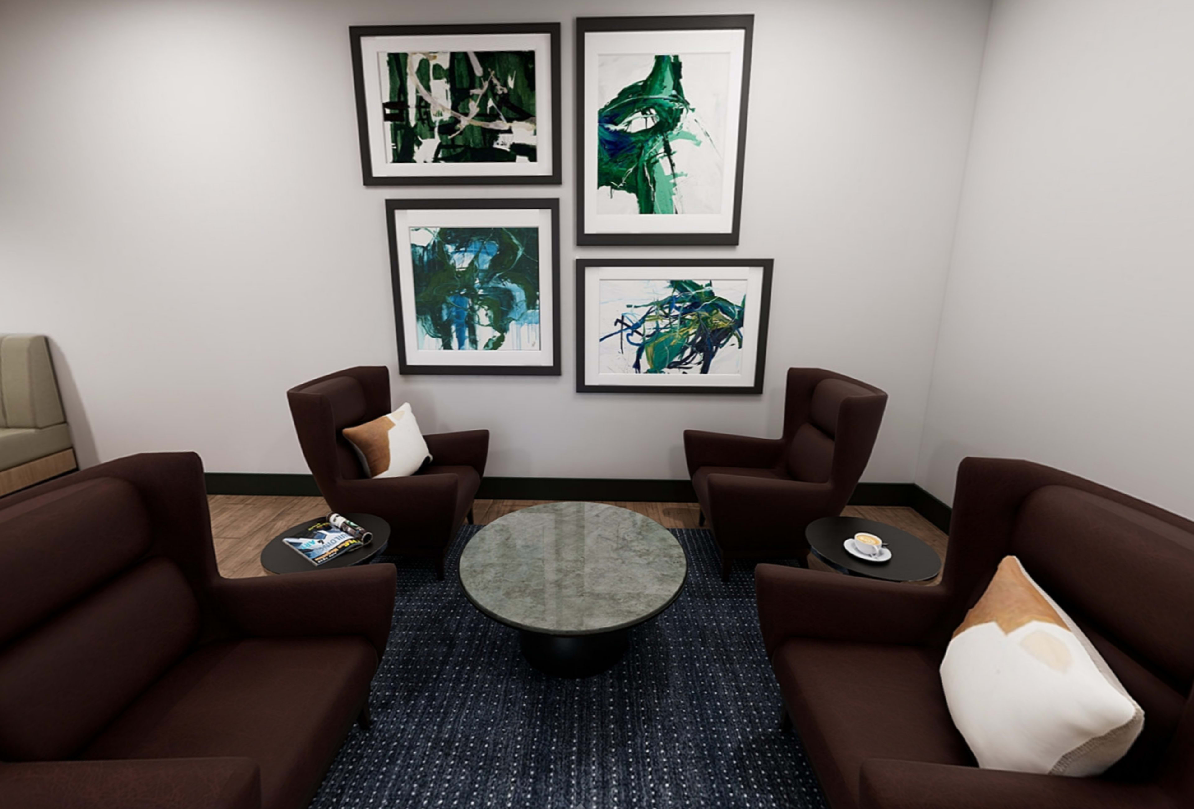 A cozy seating area with two brown armchairs, a round coffee table, and four framed abstract artworks on the wall.