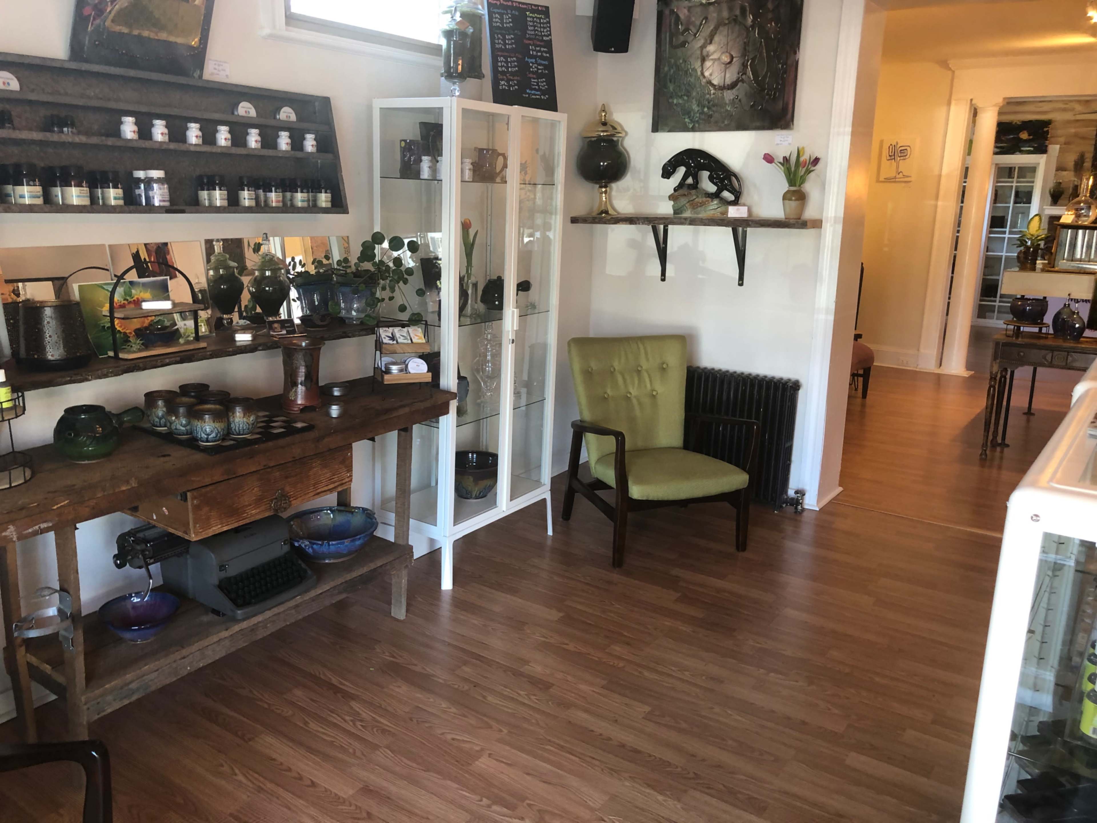 A well-lit interior of a shop featuring wooden furniture, decorative items, and a mix of plants on display.
