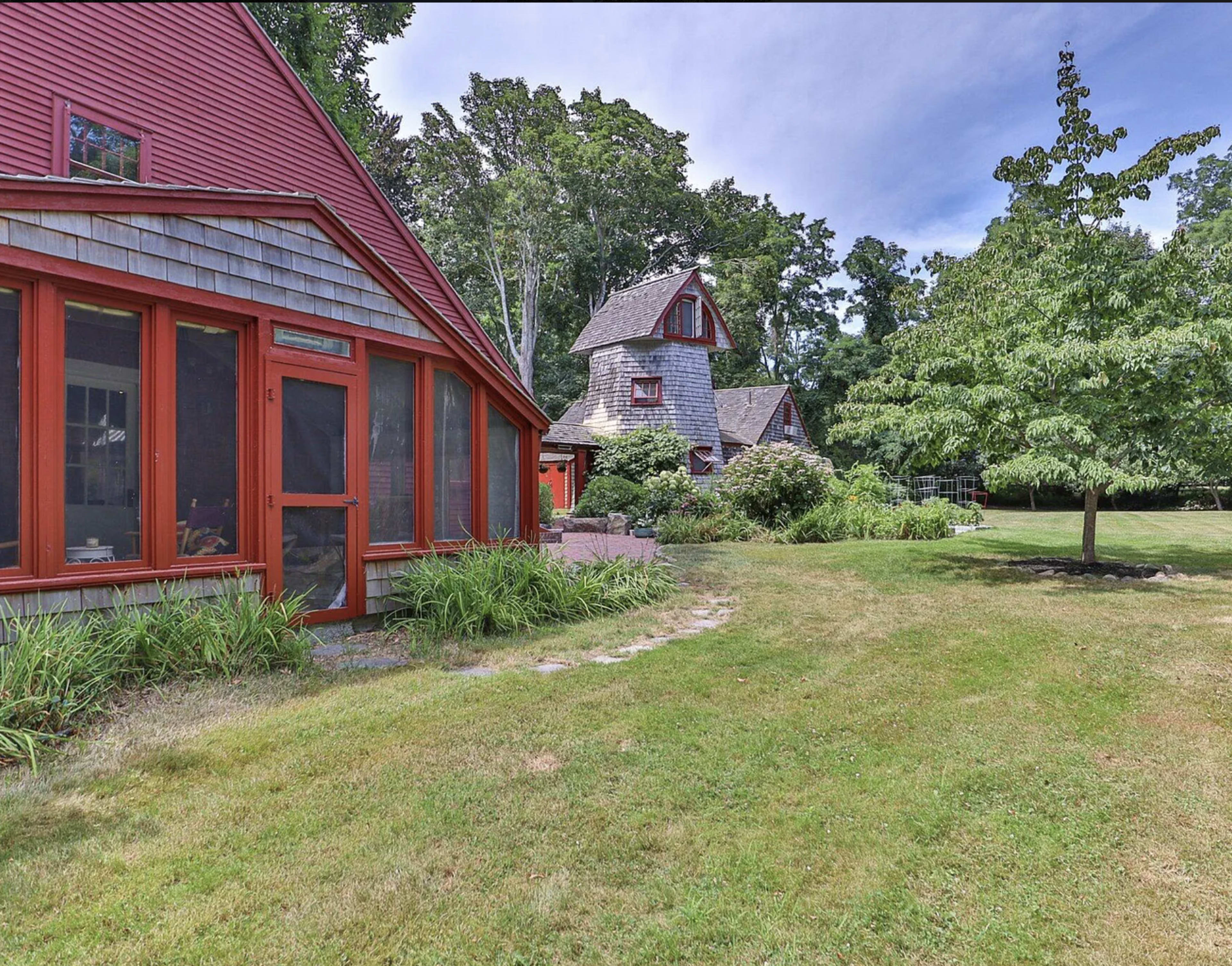 A yard with a landscaped garden featuring two distinct red-roofed buildings surrounded by greenery.