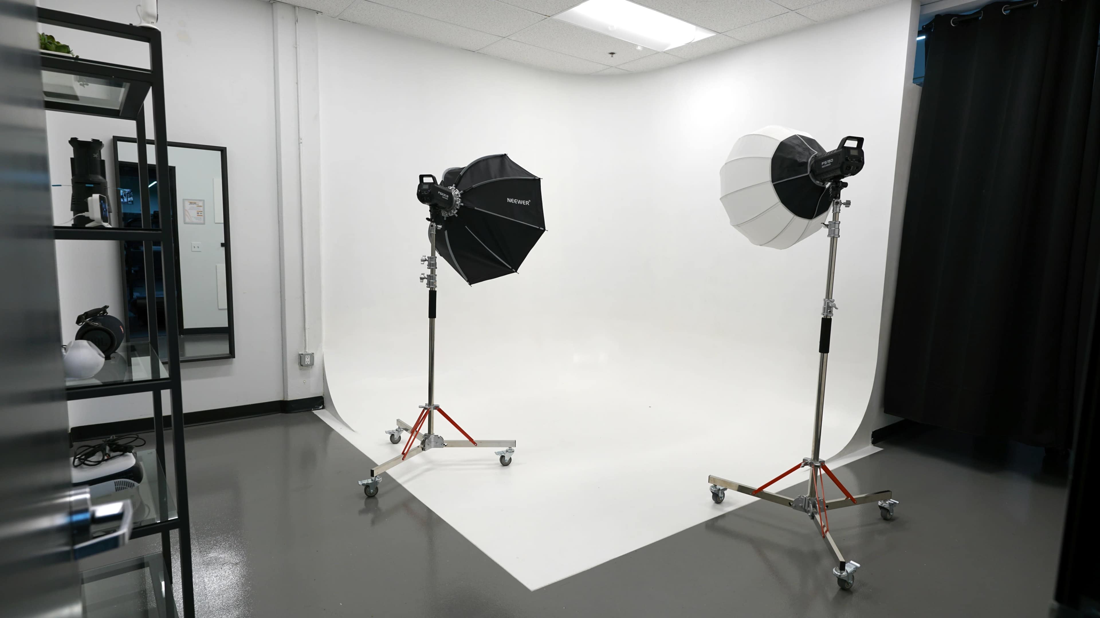 The image shows a photography studio setup with two lighting umbrellas on stands positioned against a white backdrop.