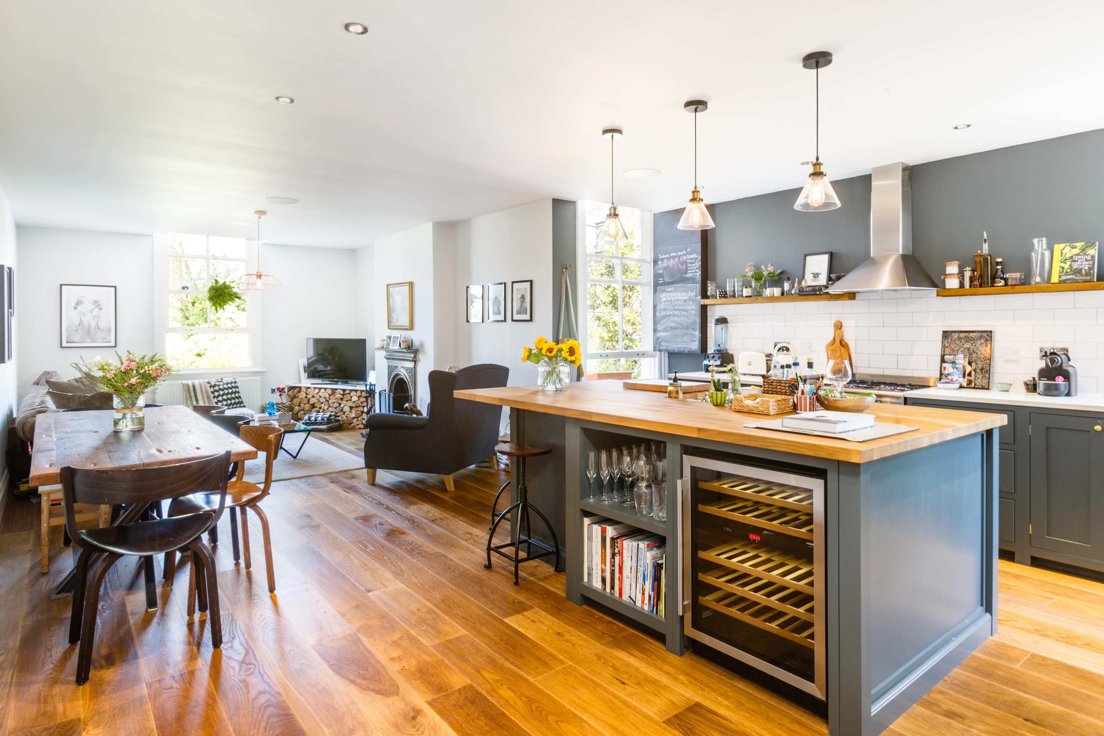 A modern open-concept kitchen and dining area features a wooden island, a dining table, and large windows that allow natural light to fill the space.