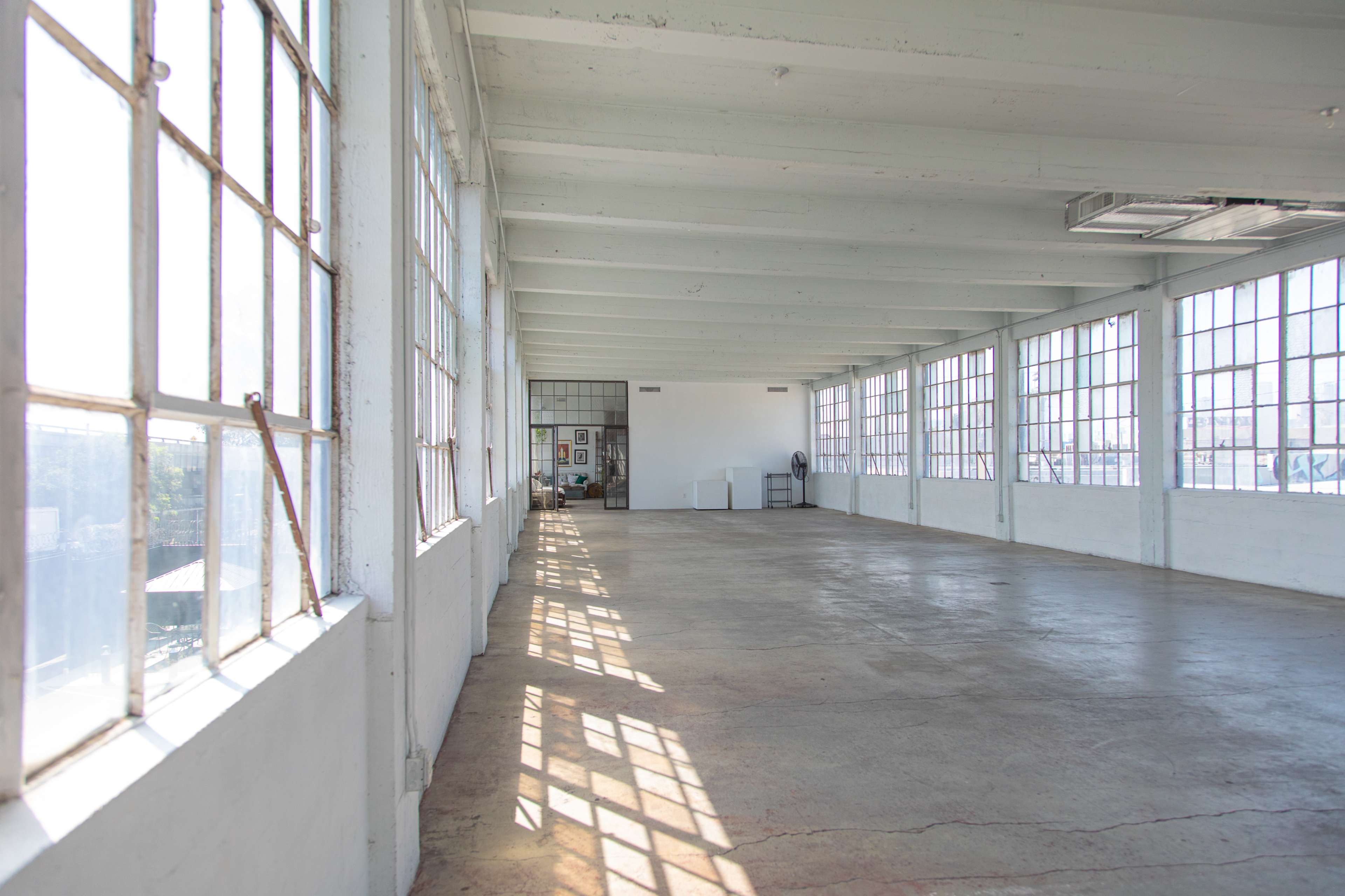 An empty industrial space with large windows allowing natural light to fill the room.