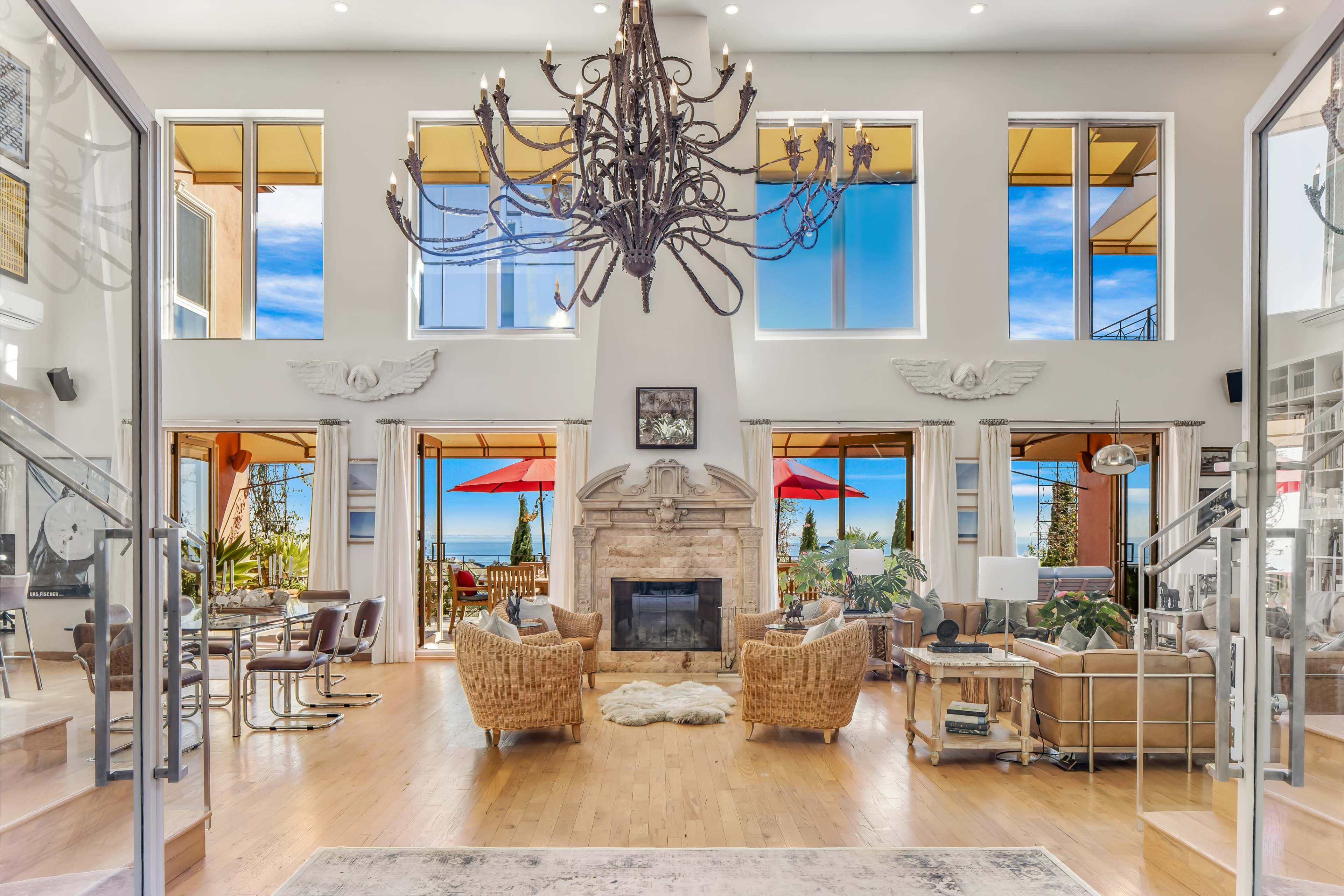 A spacious living area with large windows showcasing a view of the ocean, a central fireplace, and modern furniture arrangements.