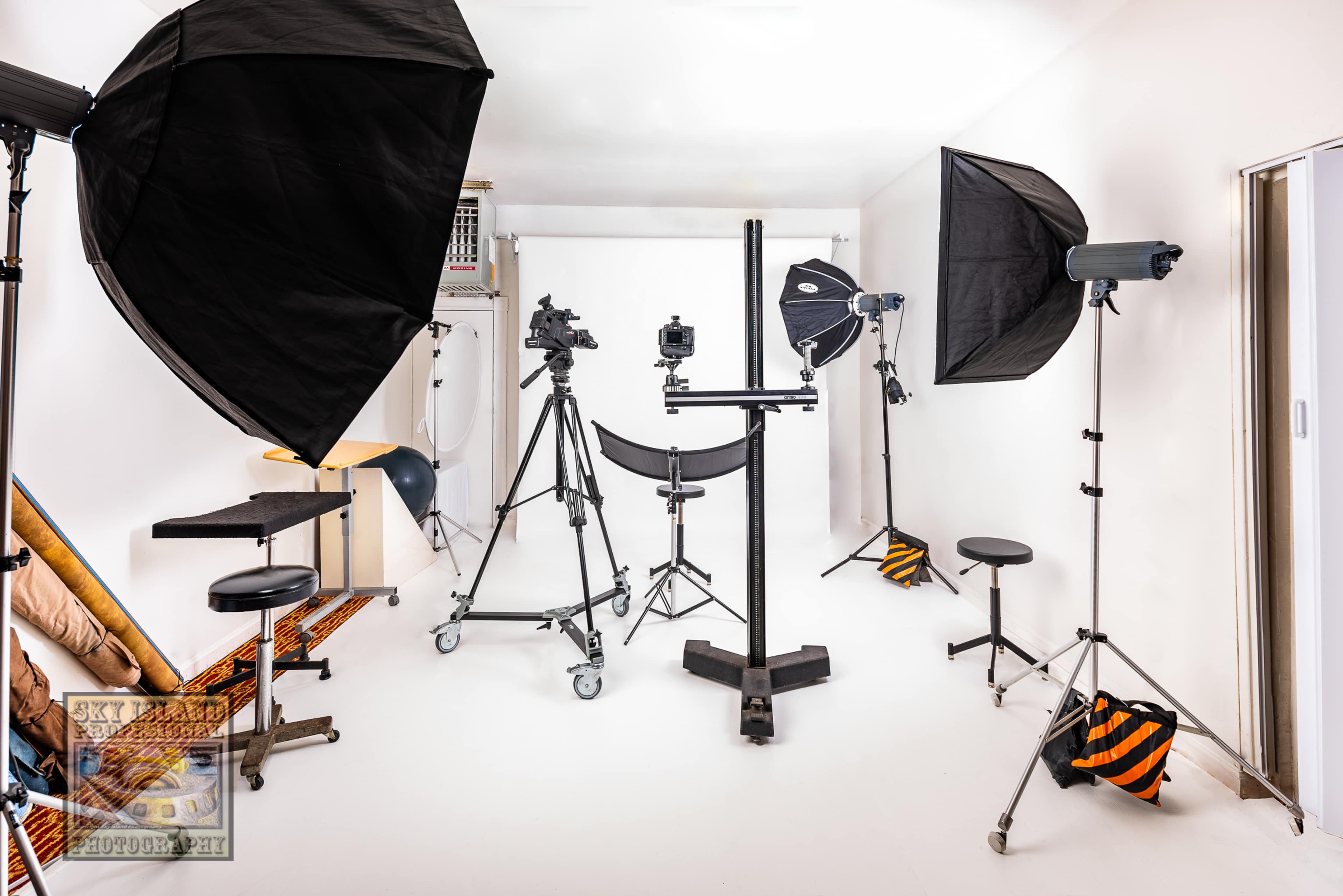 A photography studio equipped with various lighting setups and a camera on a tripod.