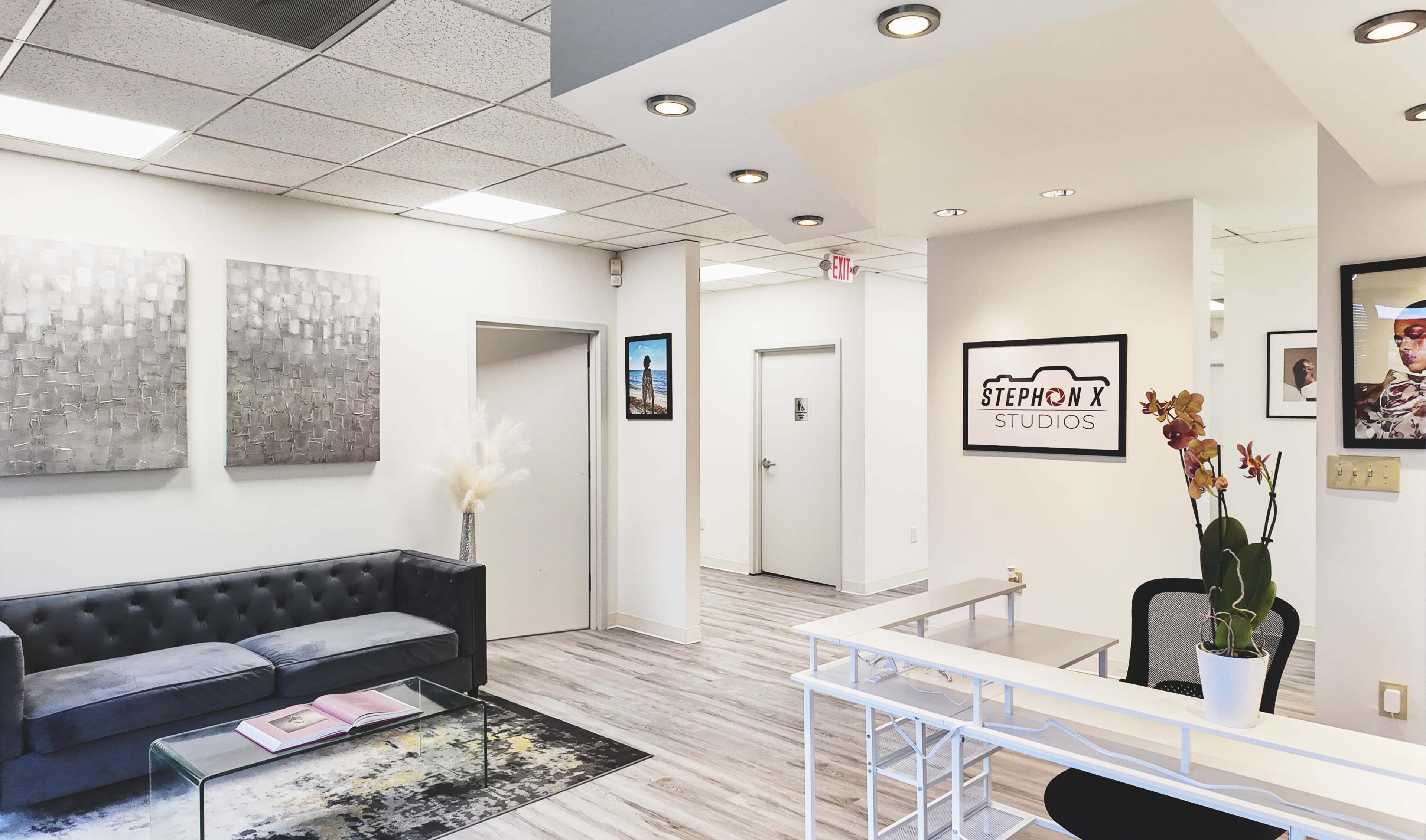 A modern reception area with a black sofa, decorative wall art, and a desk labeled "STEPHON X STUDIOS."