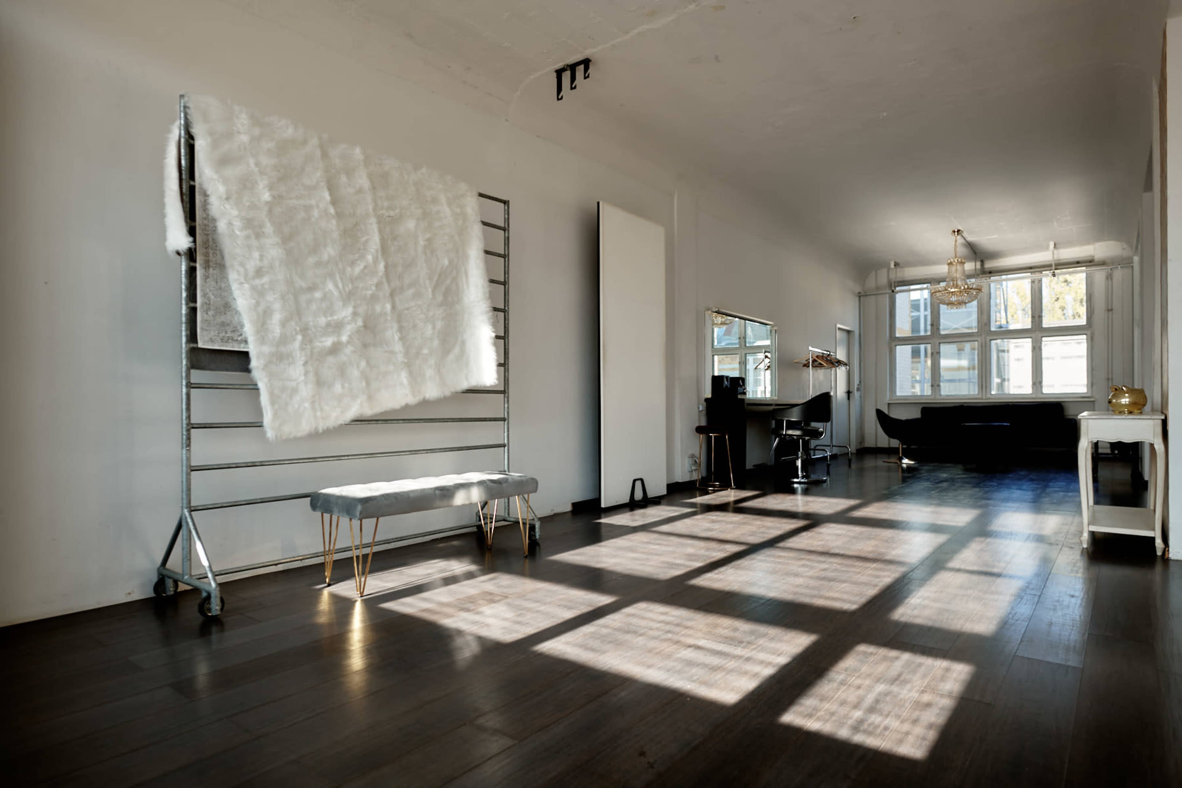 A bright, spacious interior with large windows, a sleek bench, a mirror station, and a piano in the background.