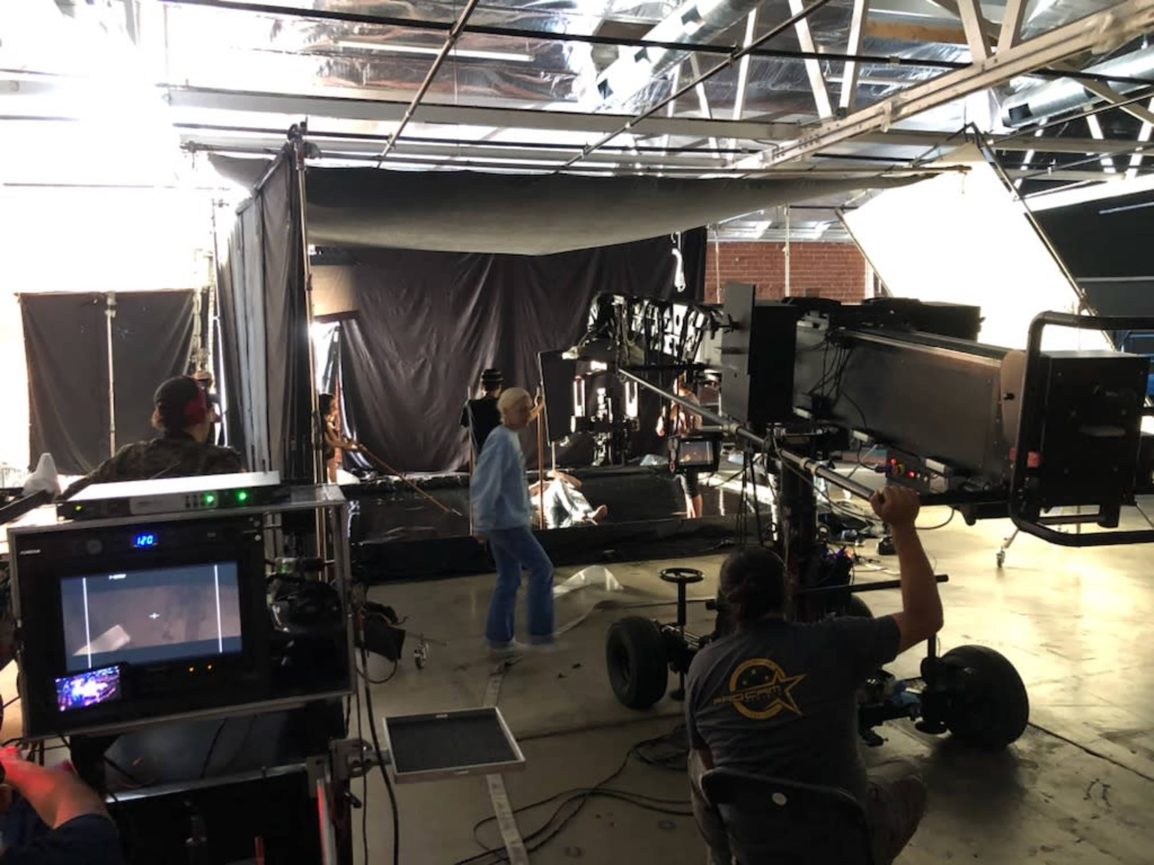 A film crew sets up equipment and adjusts lighting in a studio space for a production.