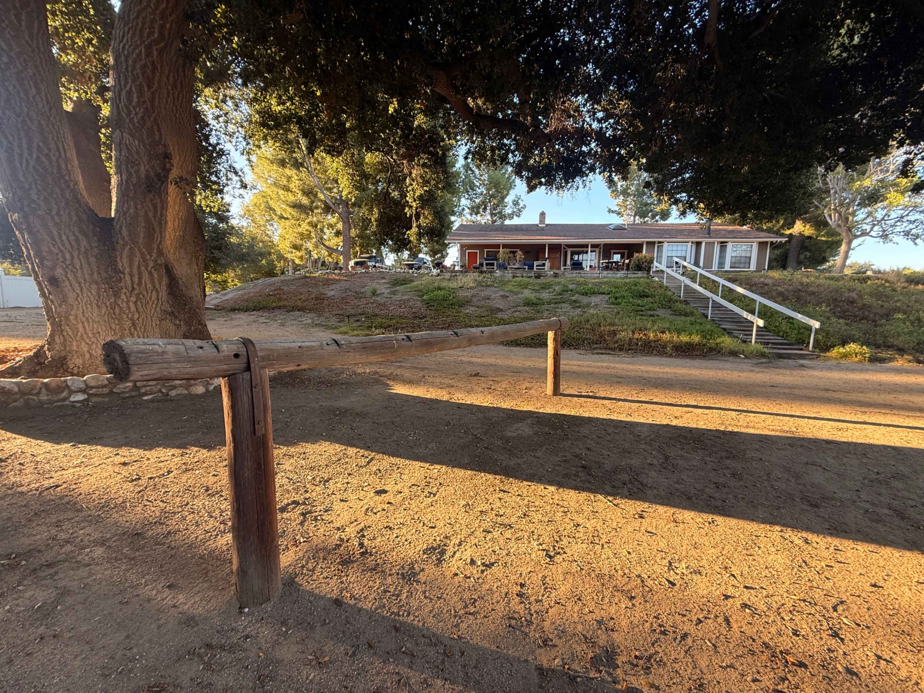 A wooden horizontal bar is positioned in the foreground with a house and trees visible in the background.
