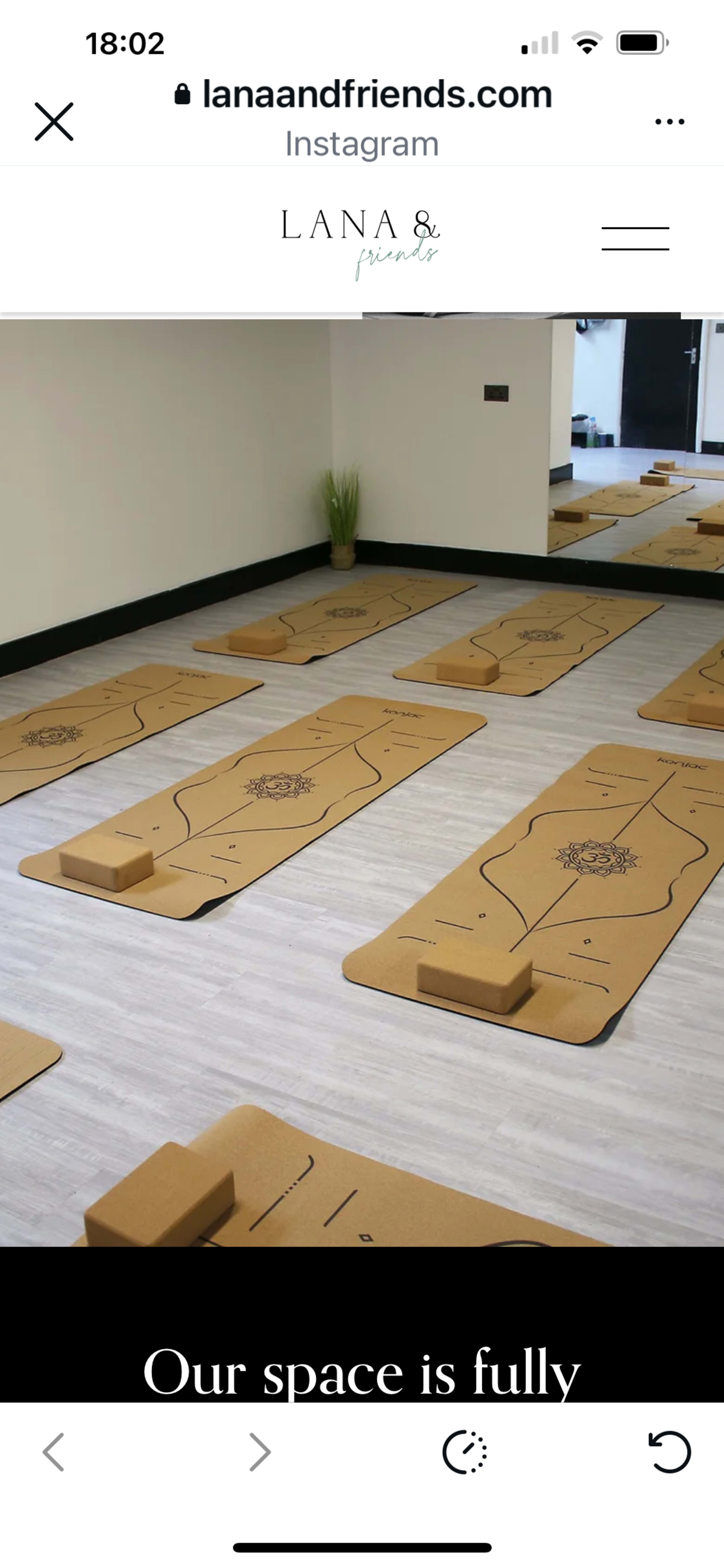 The image shows a spacious yoga studio with several yoga mats arranged on the floor.