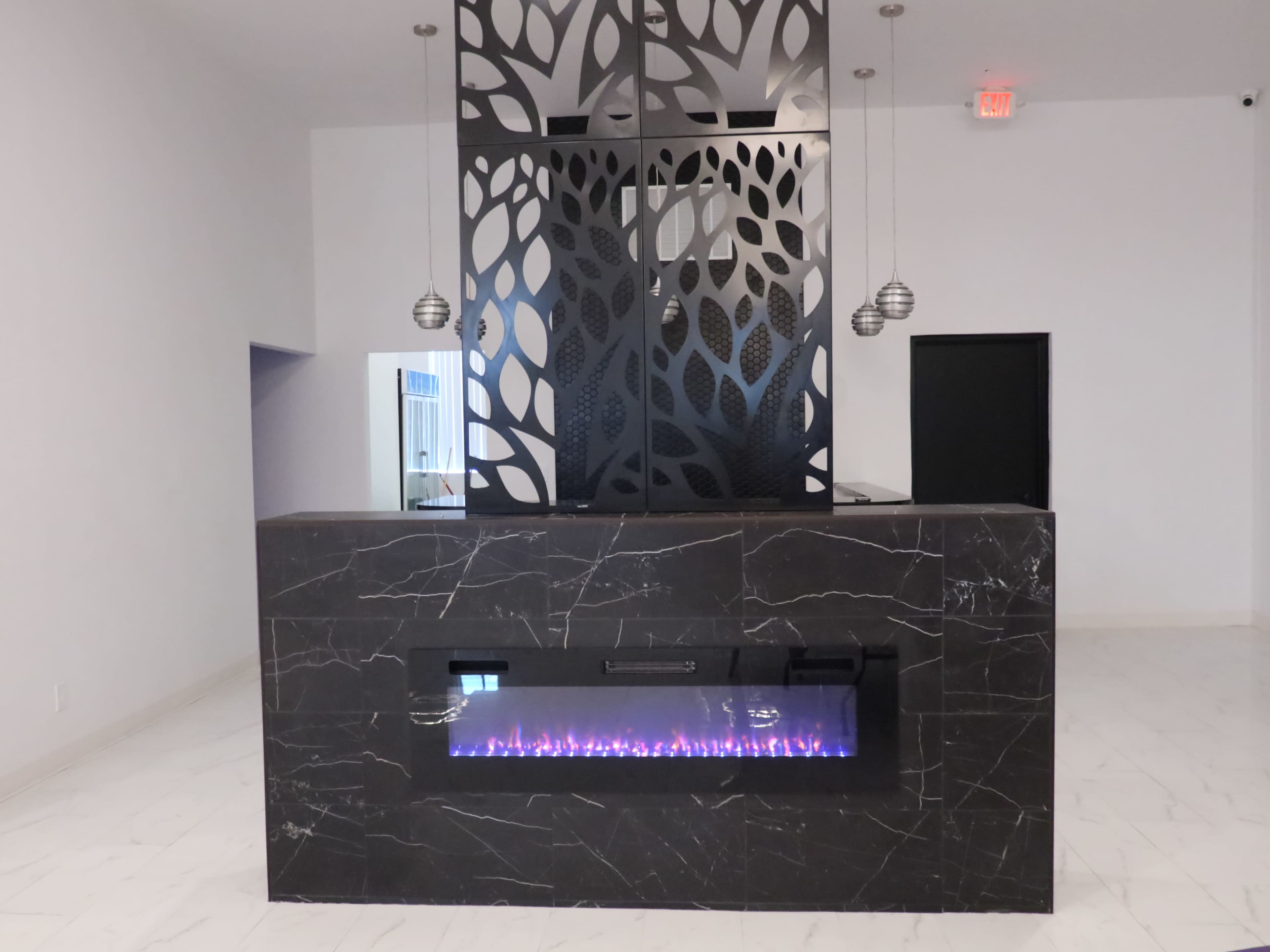 A modern interior space with a black marble fireplace and a decorative screen with leaf patterns.