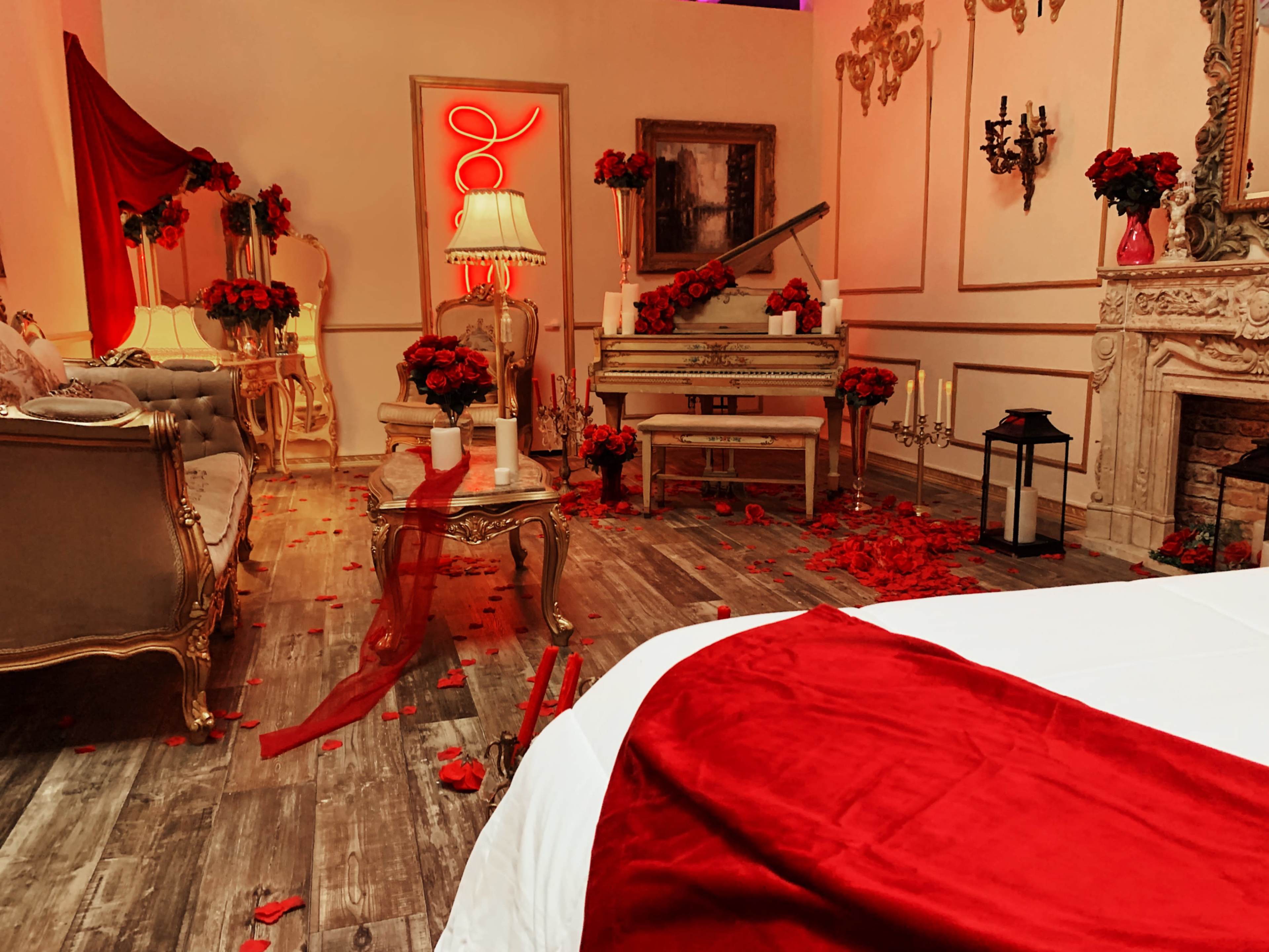 The scene depicts an elegantly arranged room with a white piano adorned with red roses and scattered rose petals, featuring vintage furniture and soft lighting.