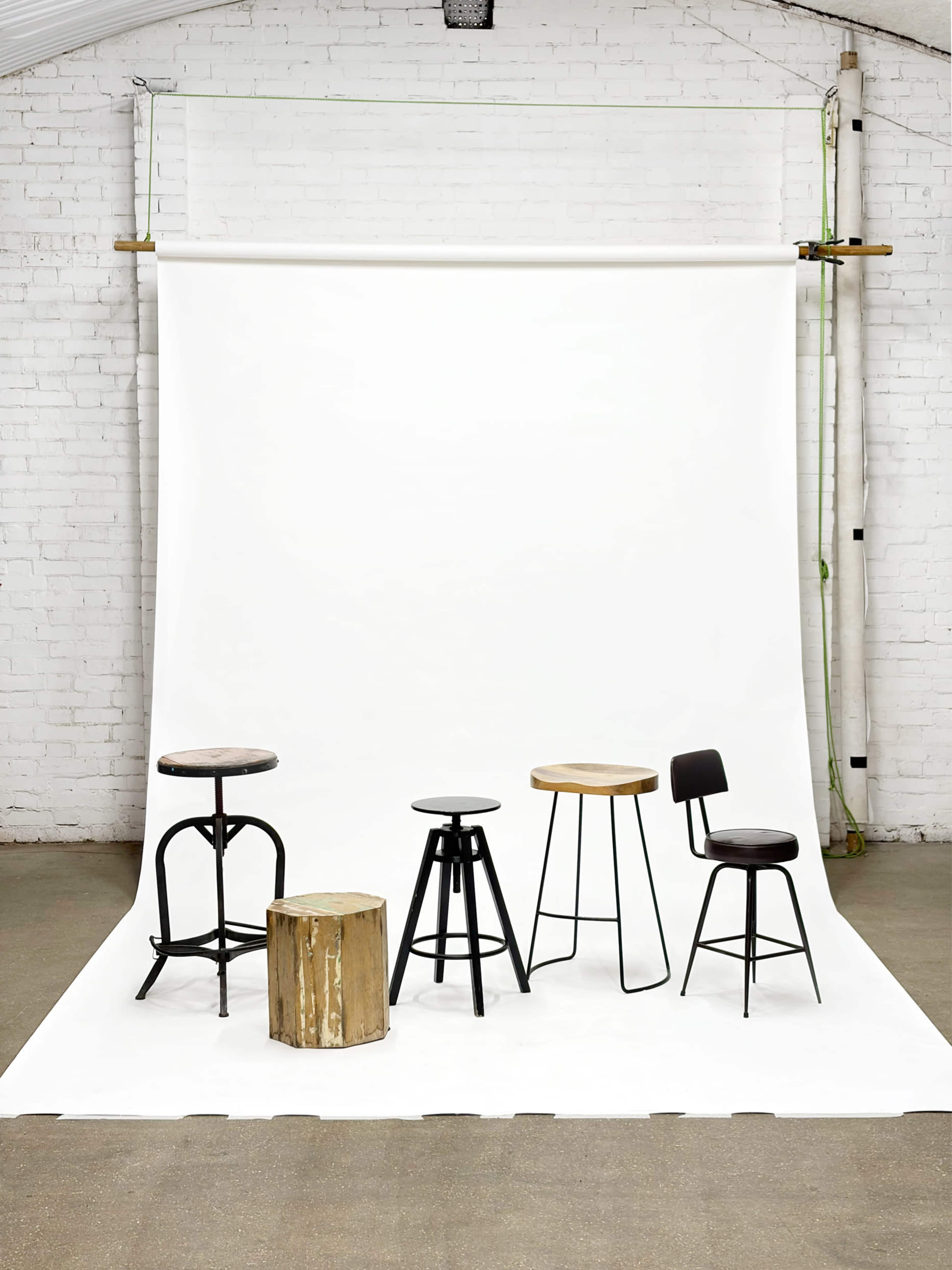 The image features a collection of five different stools displayed in front of a plain white backdrop in an indoor setting.