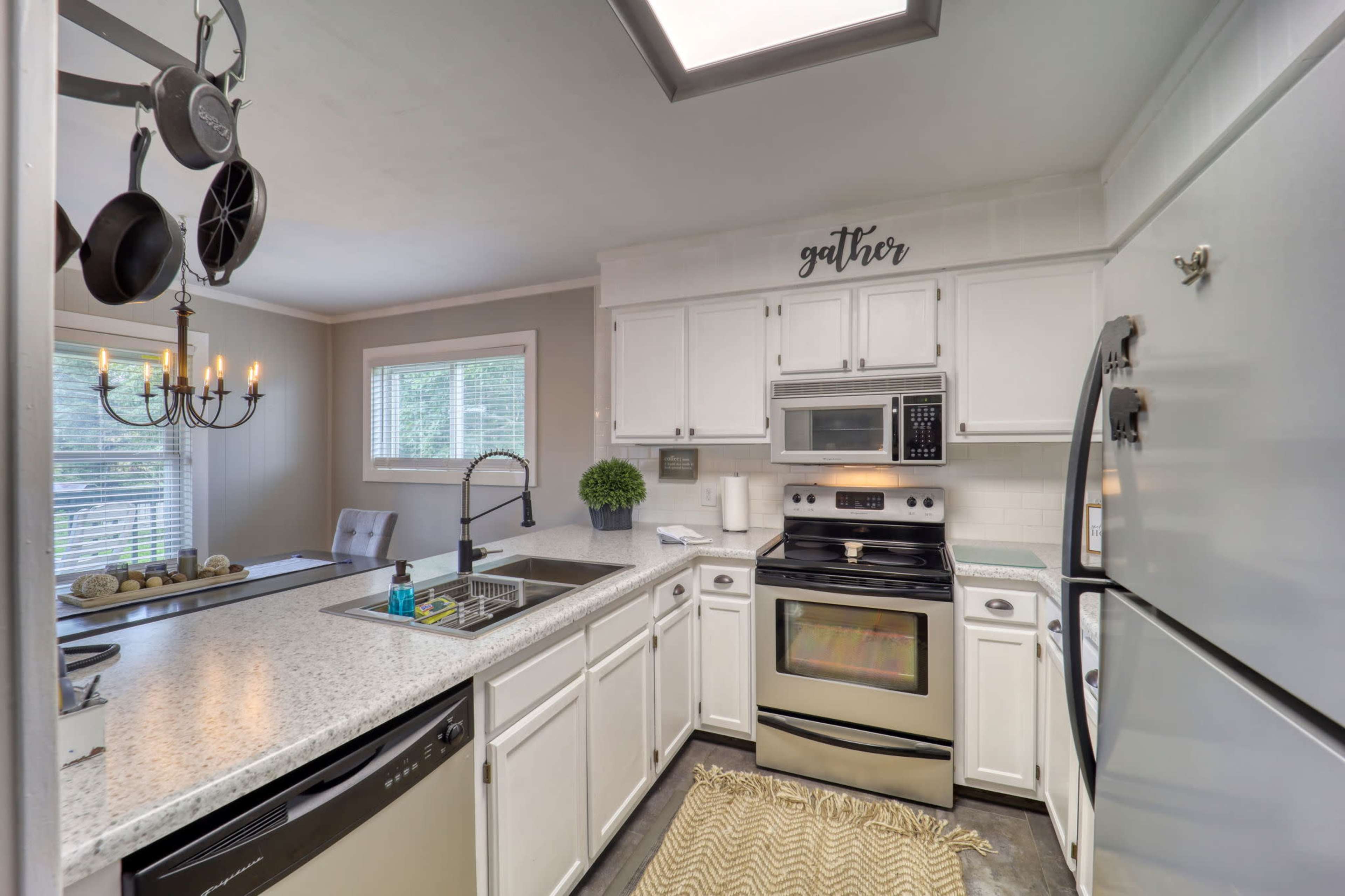 A modern kitchen features white cabinetry, stainless steel appliances, and a central island with seating.