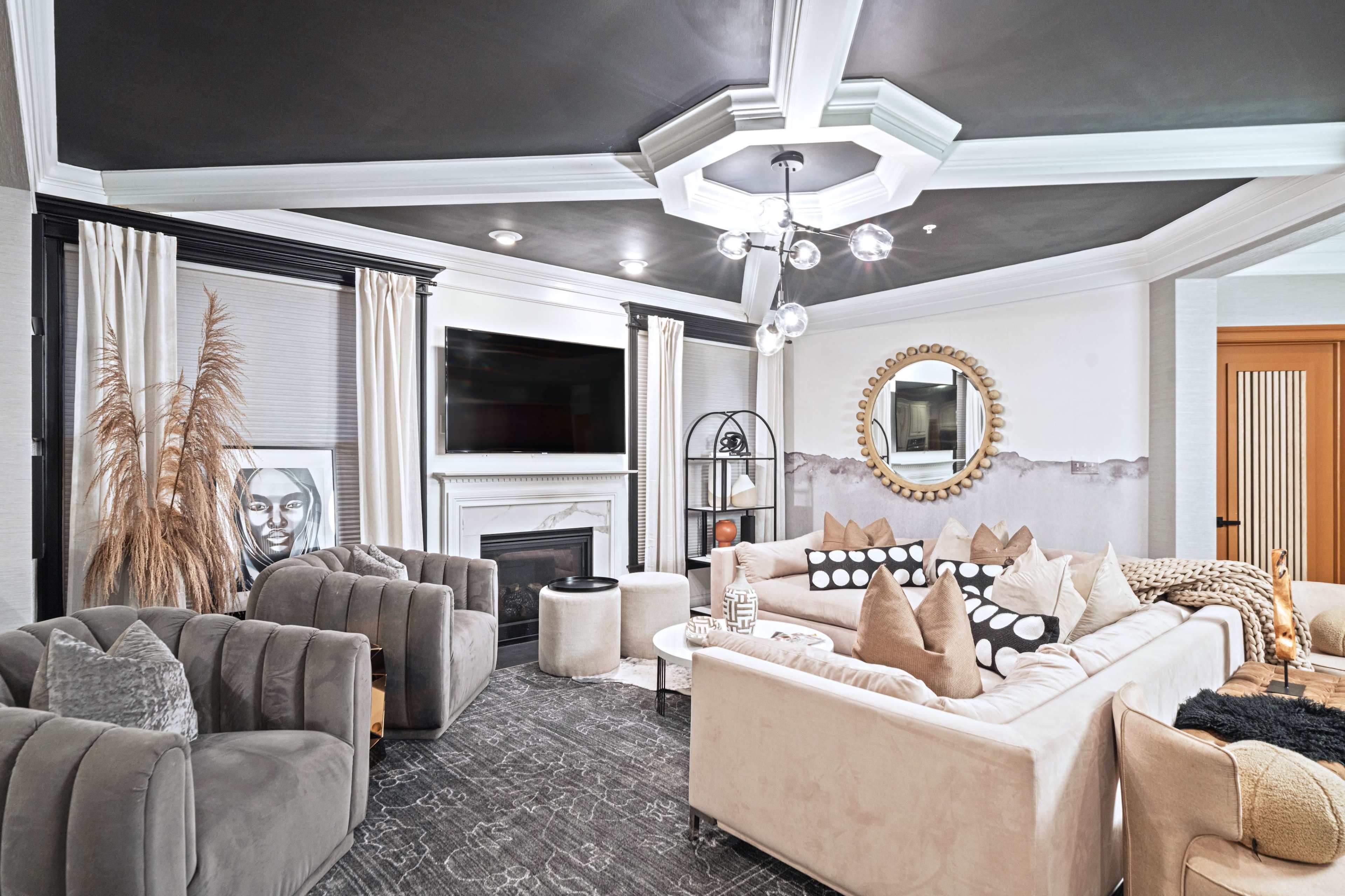 A modern living room with a sectional sofa, several decorative pillows, a coffee table, and a fireplace, all arranged under a coffered ceiling.