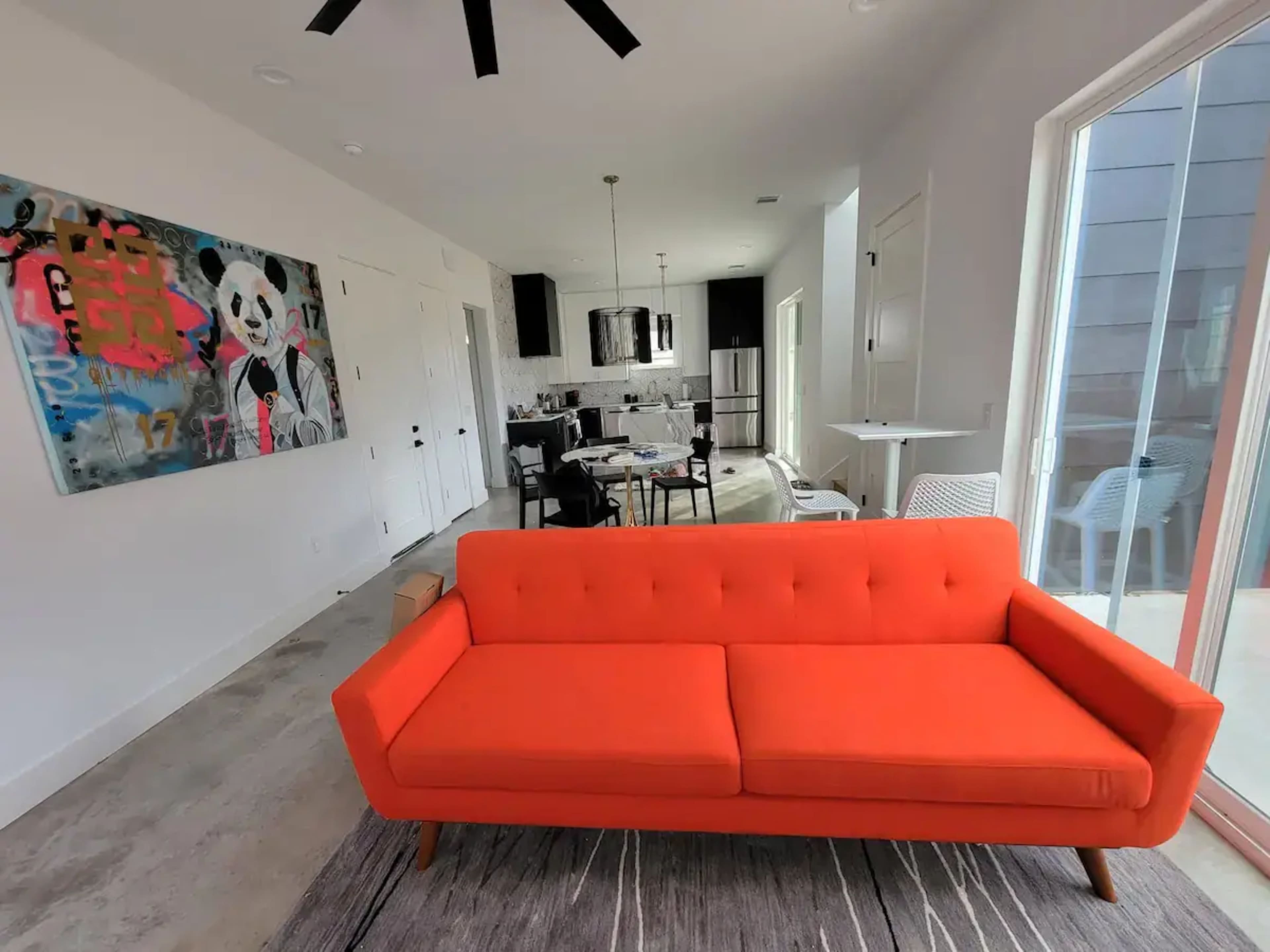 An orange sofa in a contemporary living space, with a dining area and kitchen visible in the background.